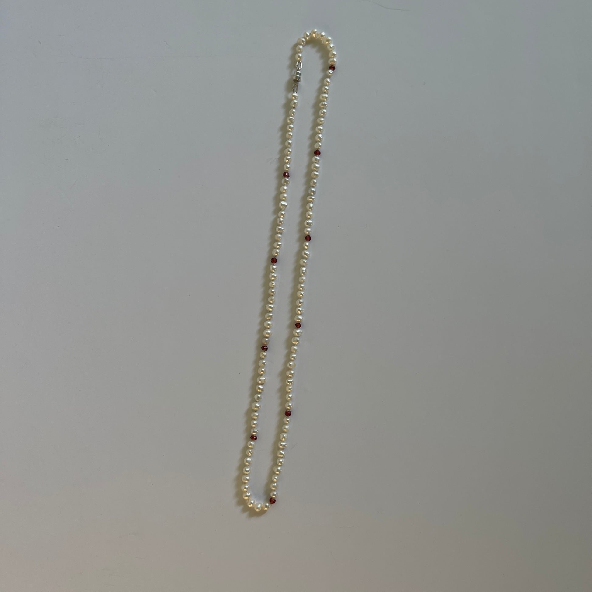 Pearl  and red cubic zirconia necklace with a white background