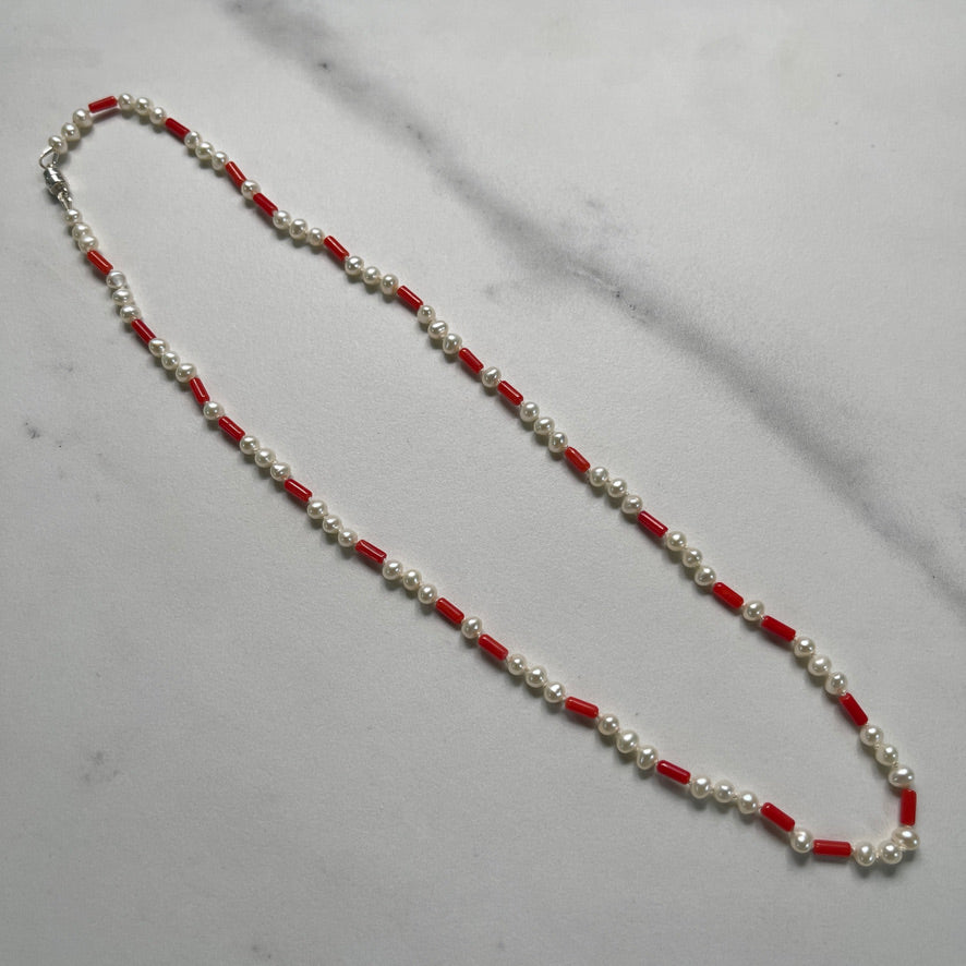 Necklace with alternating red and white beads on a gray surface