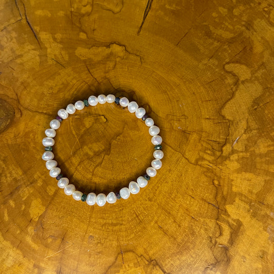 White freshwater Pearls with tiny faceted Jasper on elastic, 7 1/2" on a wooden surface
