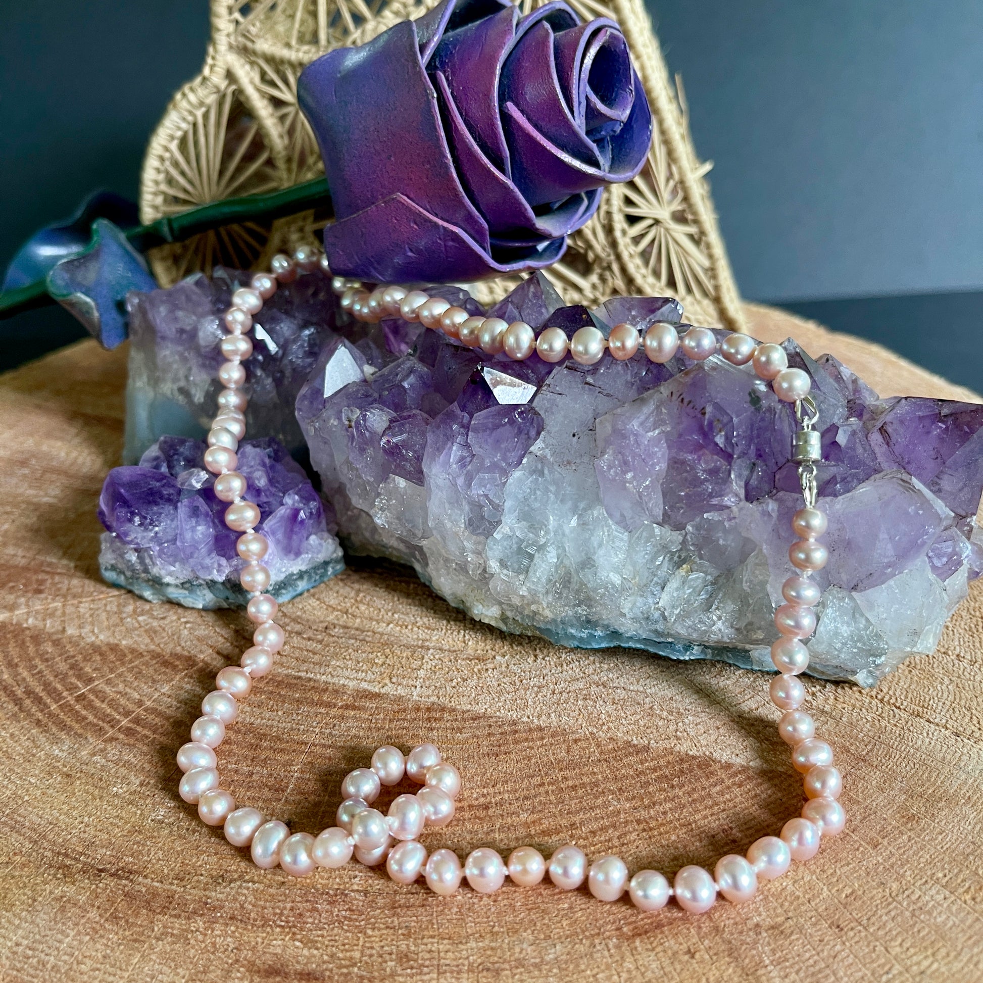 Pink Pearl necklace on a wooden surface with purple crystal and decorative rose