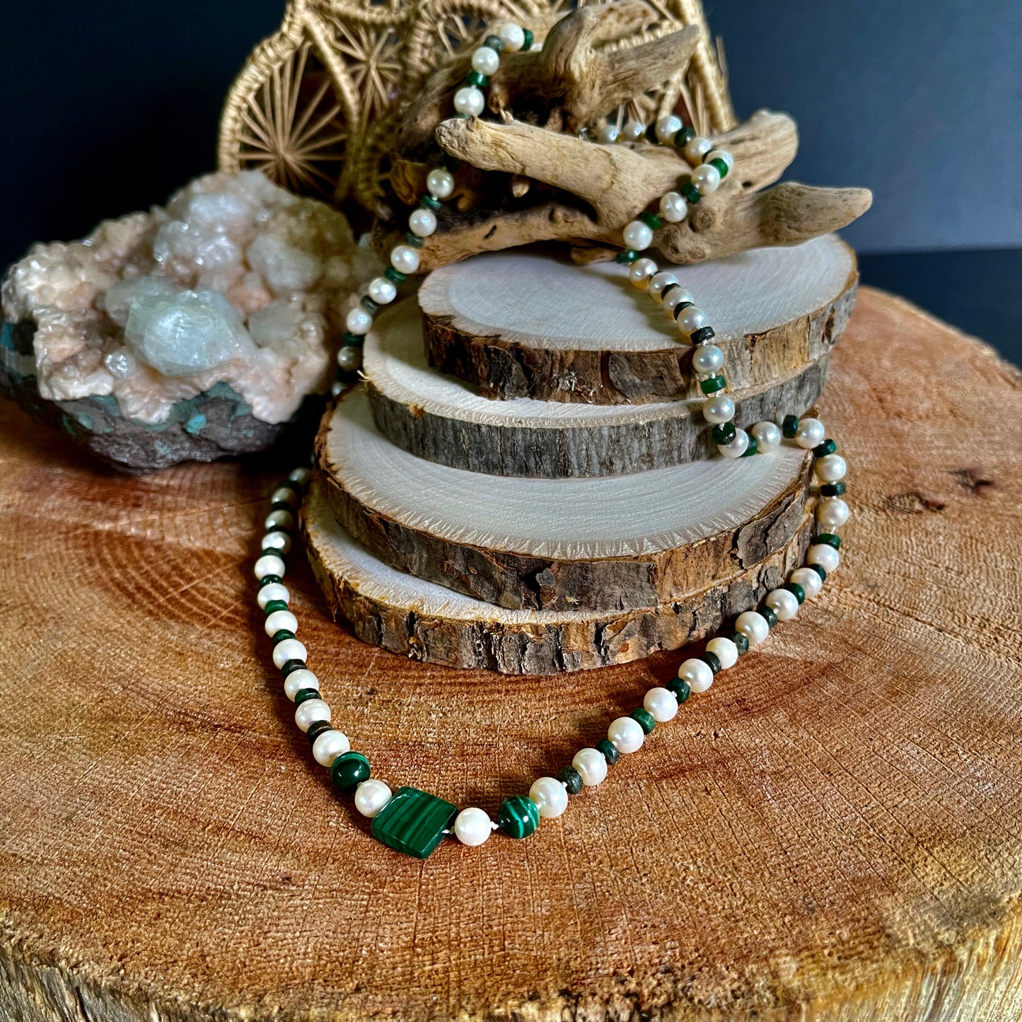 Necklace  of Malachite  and White Pearls beads on a wooden surface with natural elements