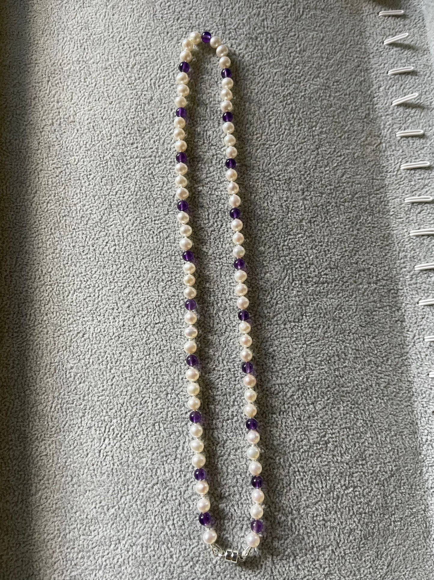 Necklace with White Pearls and Amethyst beads on a grey surface