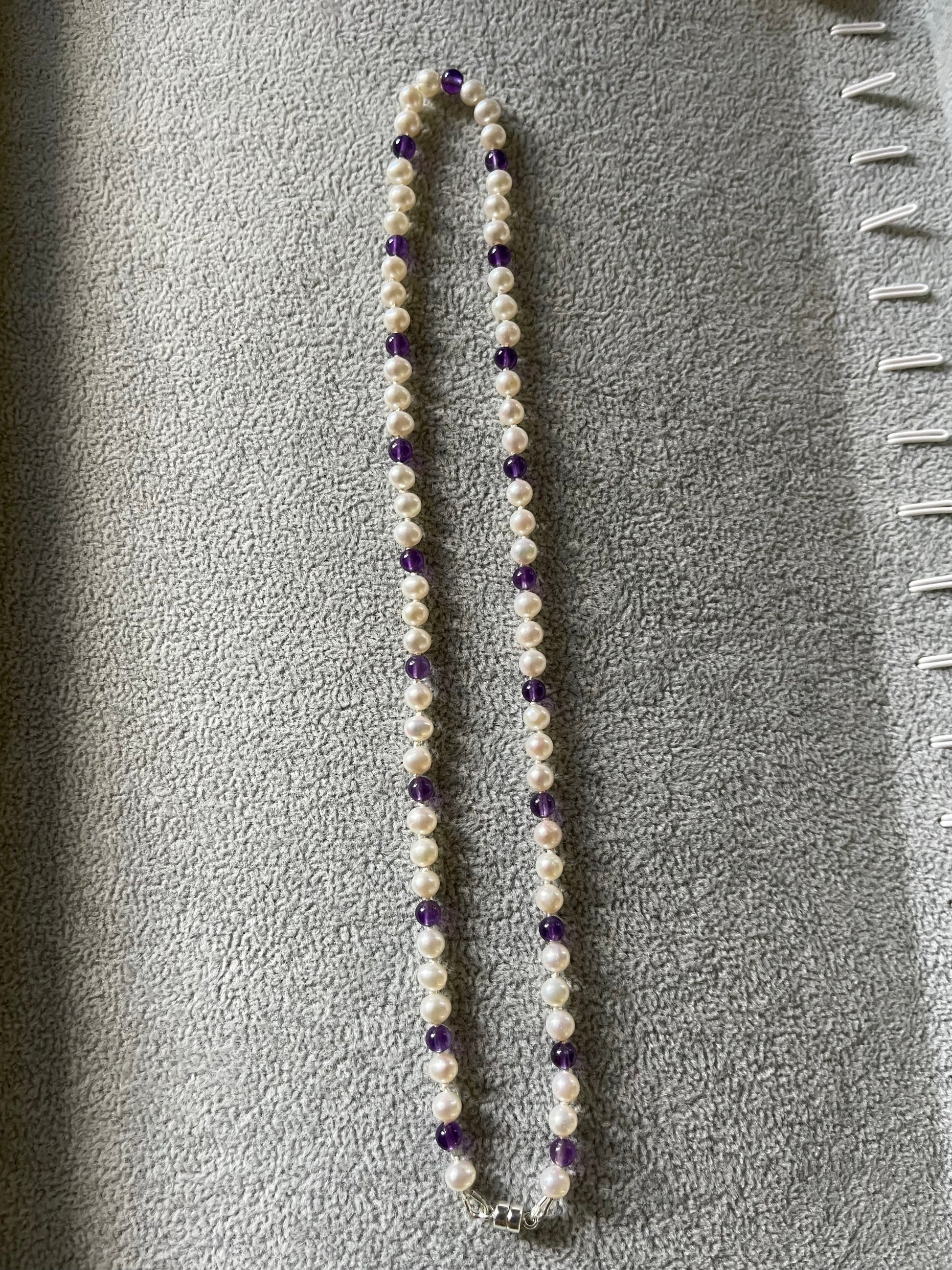 Necklace with White Pearls and Amethyst beads on a grey surface