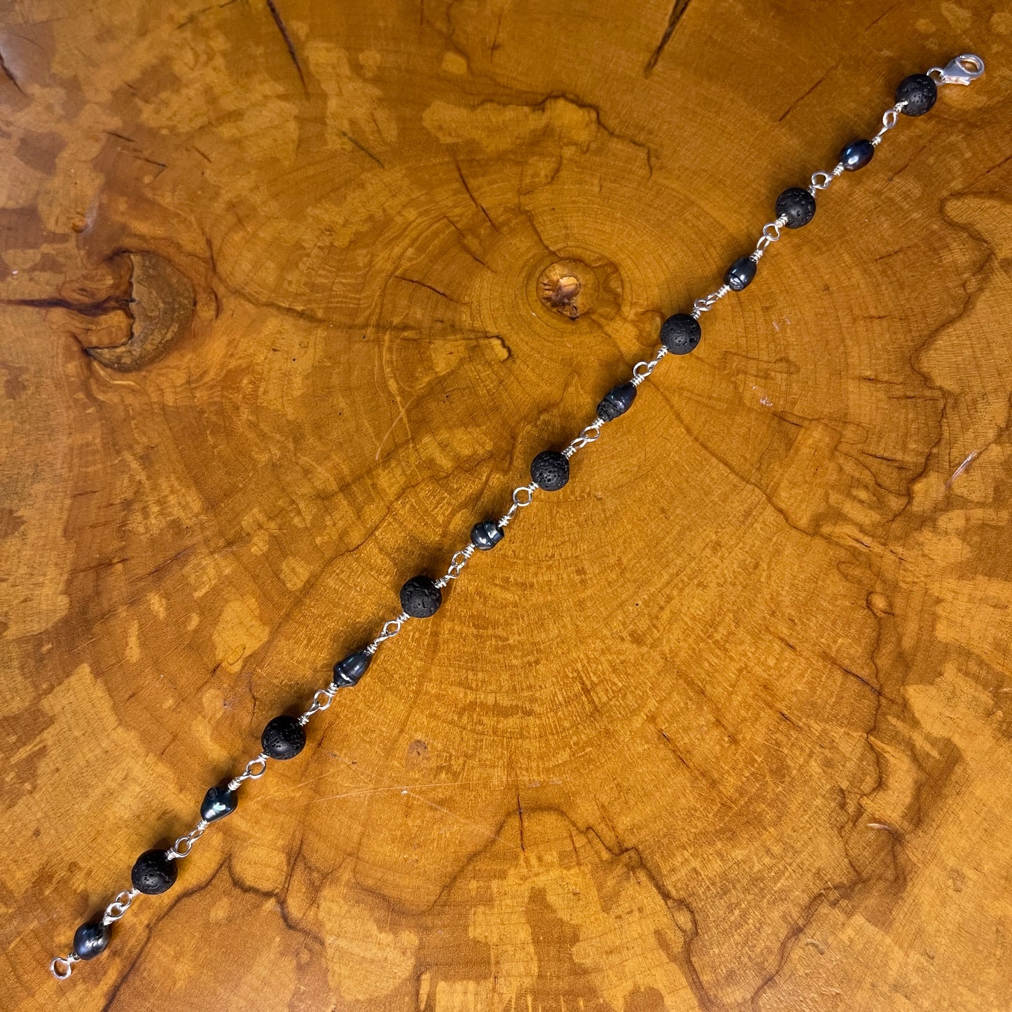 Dark Peacock Freshwater Pearls and Lava beads on Sterling Silver wire with Sterling Silver Lobster clasp, 8" on wood