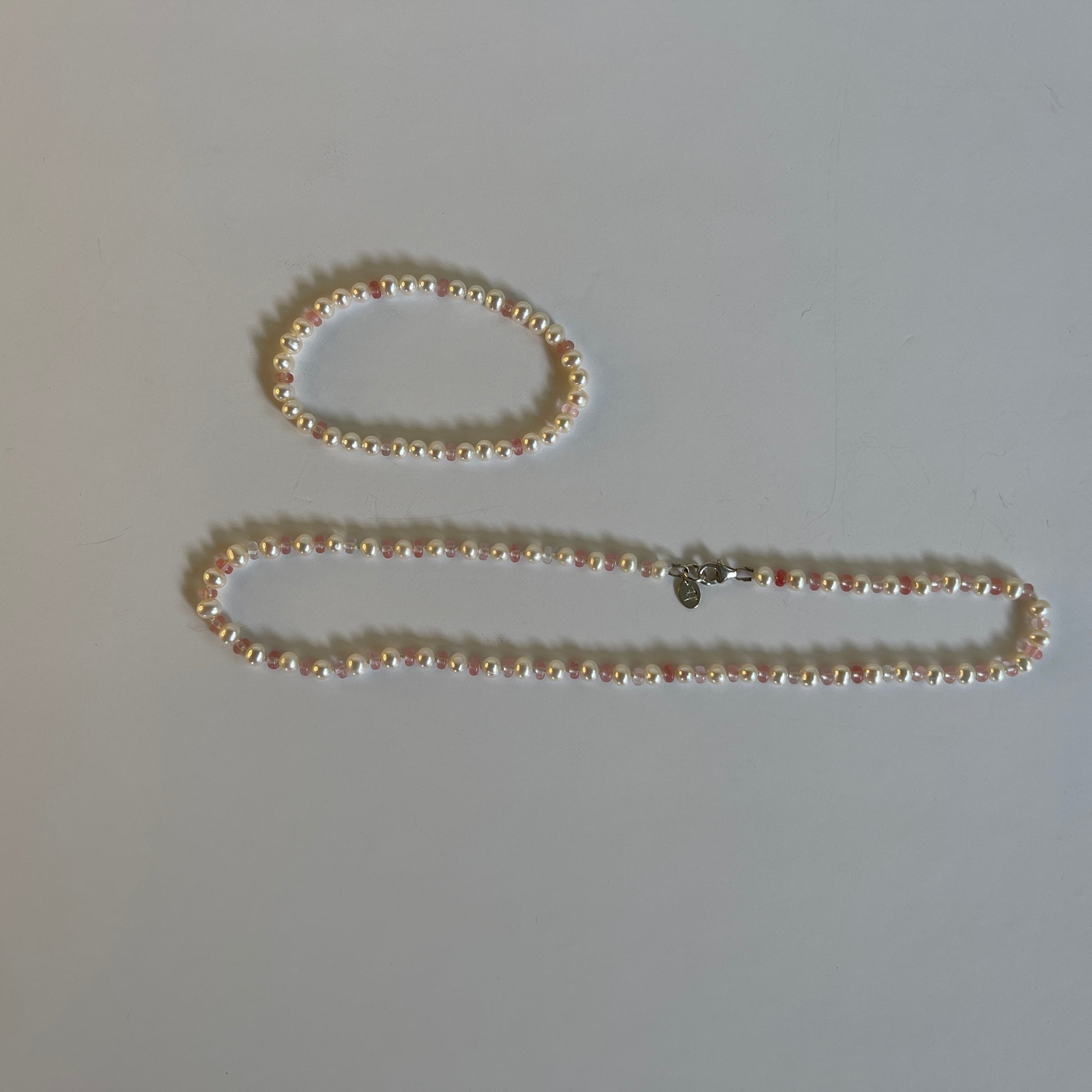 White Pearl  and strawberry quartz necklace and matching stretchy bracelet on a white background