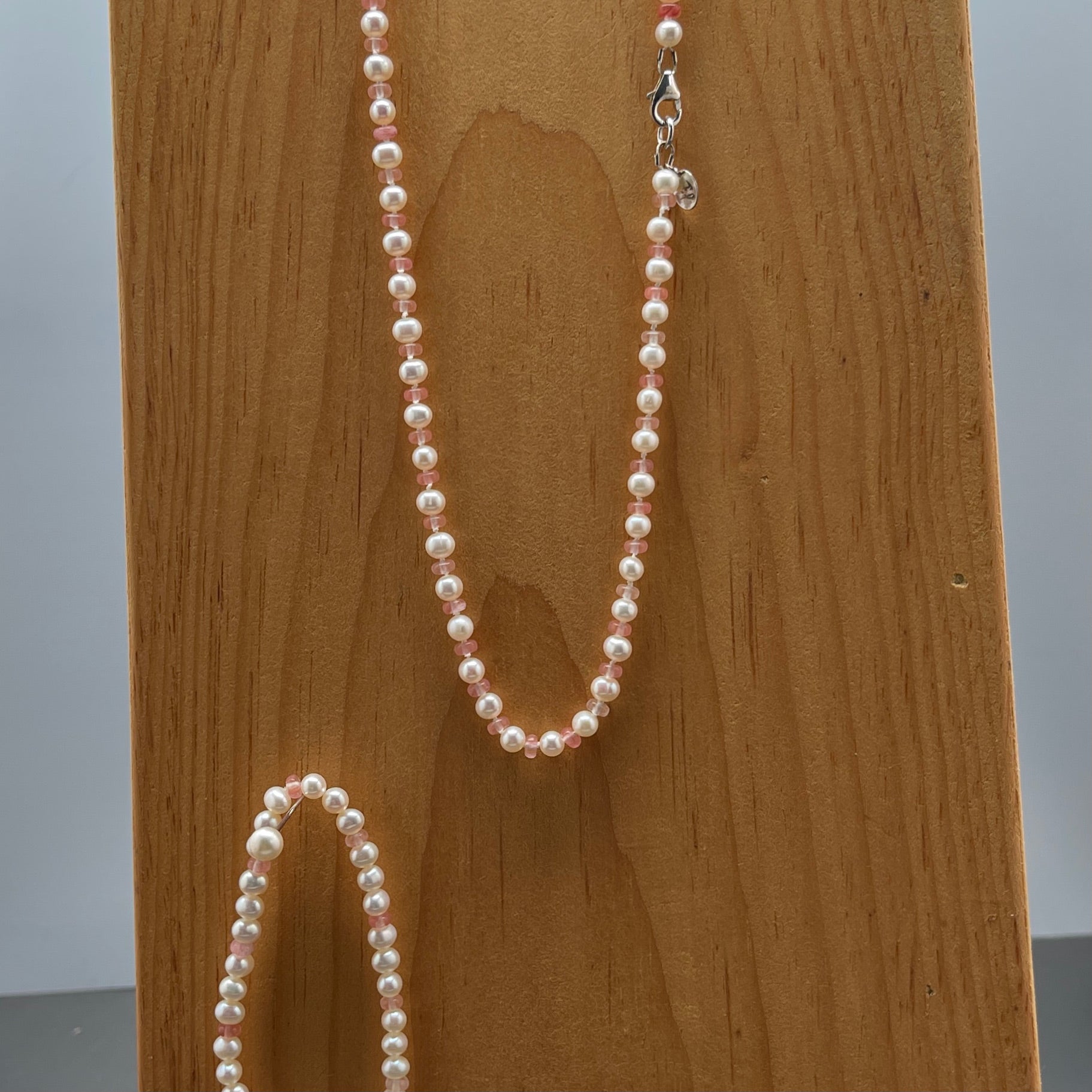 White Pearl  and strawberry quartz necklace and matching stretchy bracelet on a wooden surface 