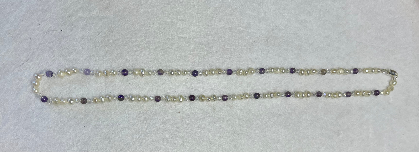 Necklace with white Pearls, Amethyst and crystals on a white surface