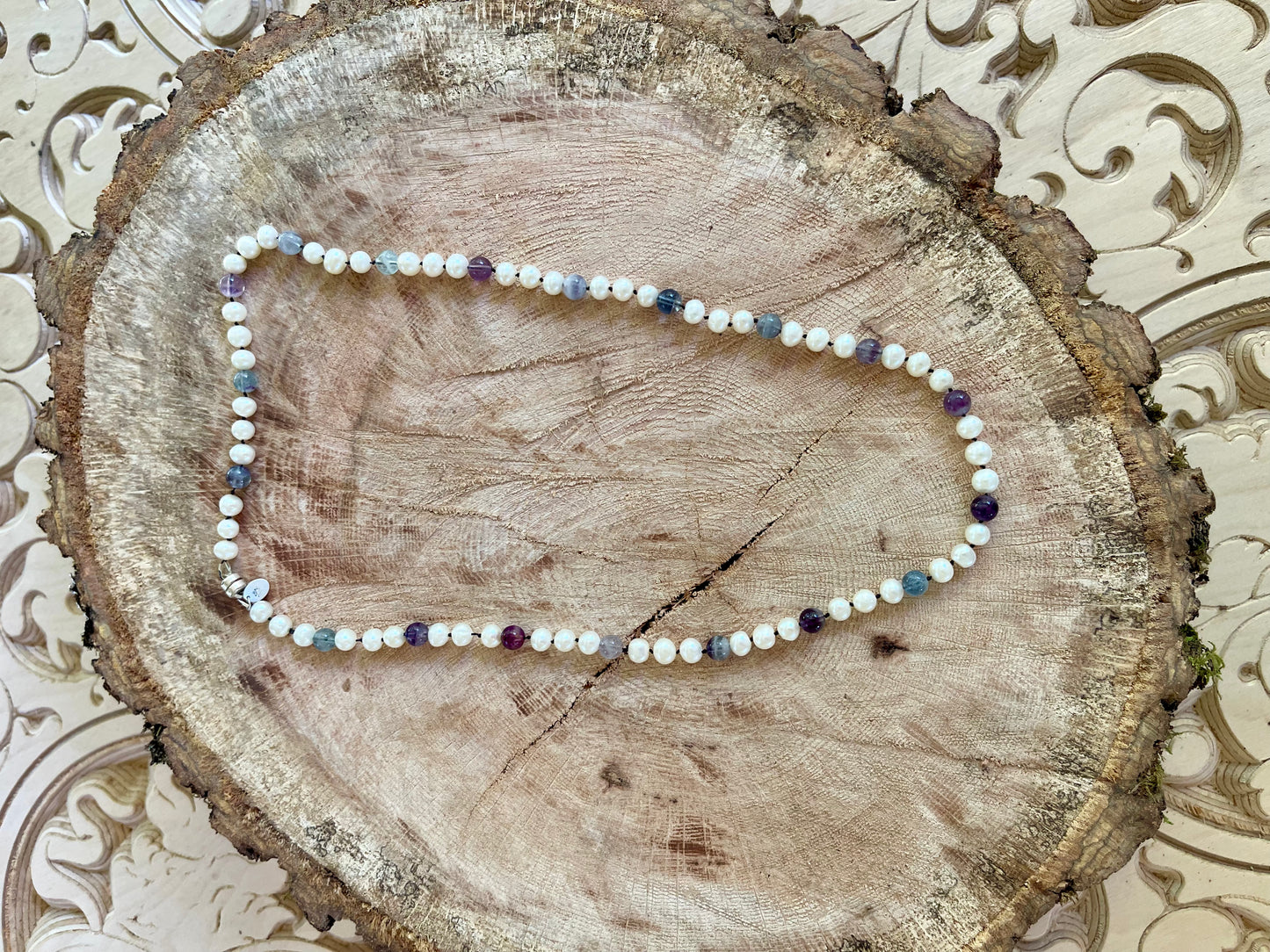 White freshwater Pearls and Fluorite necklace on a wooden surface