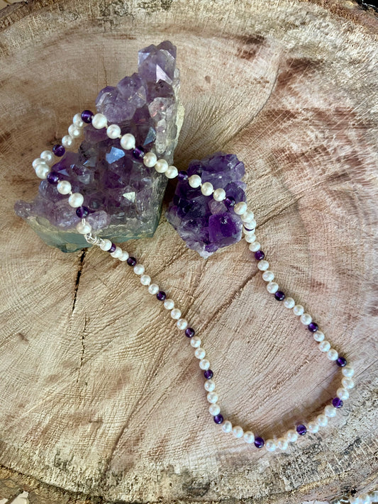 Necklace with White Pearls and Amethyst beads on a wooden surface with crystals