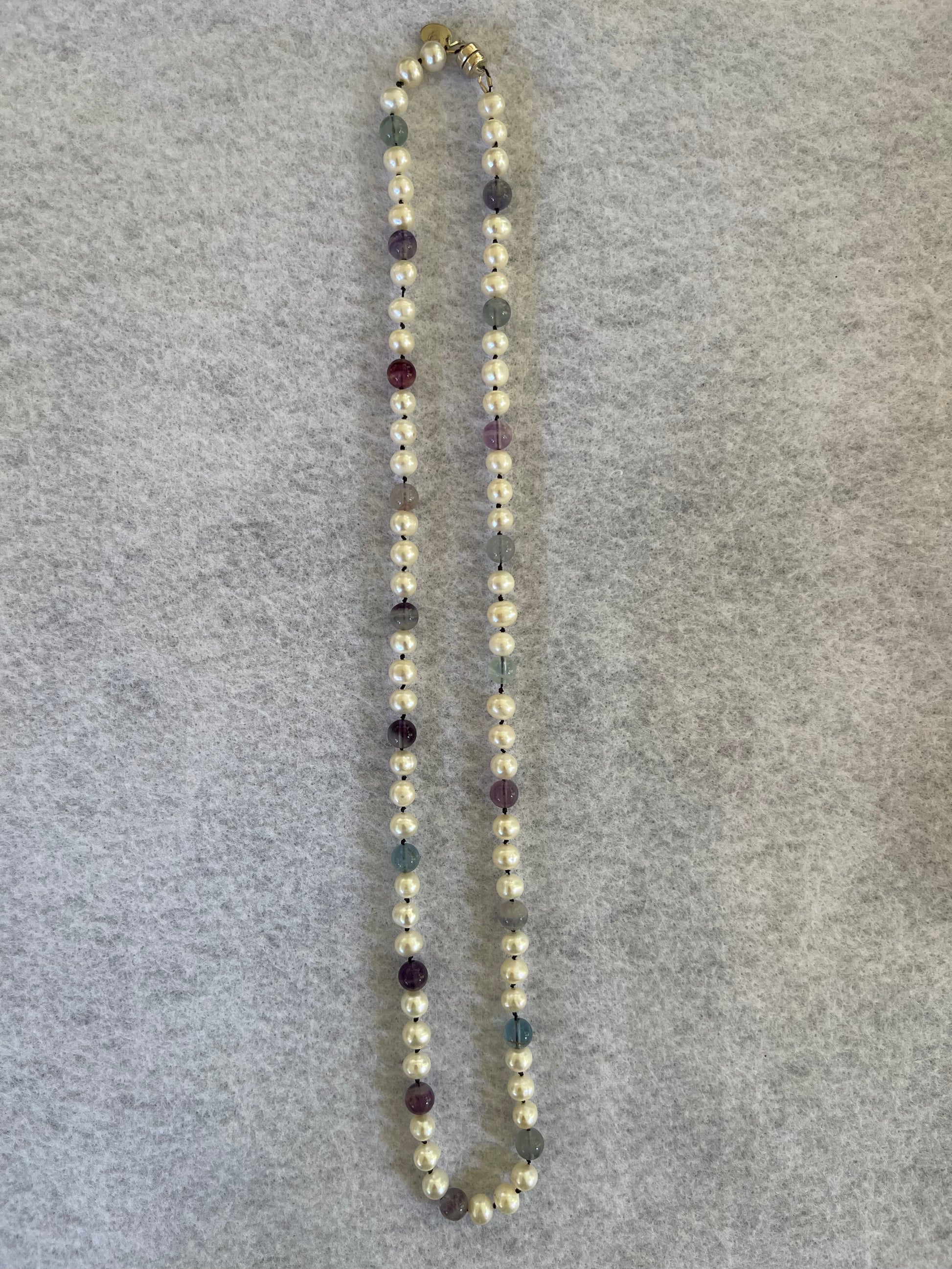 White Pearl and Fluorite beaded Necklace on a gray background