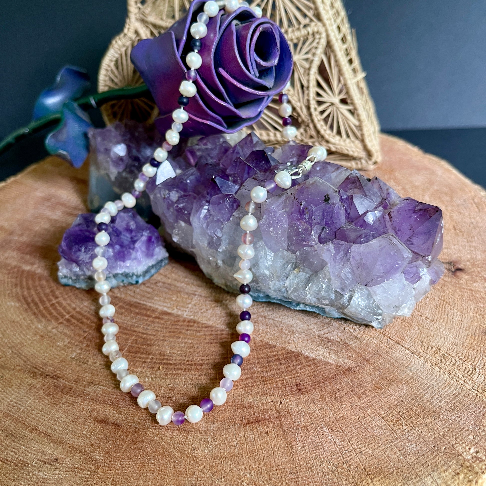 Necklace with purple Jasper and Pearl beads on a wooden surface with amethyst crystals