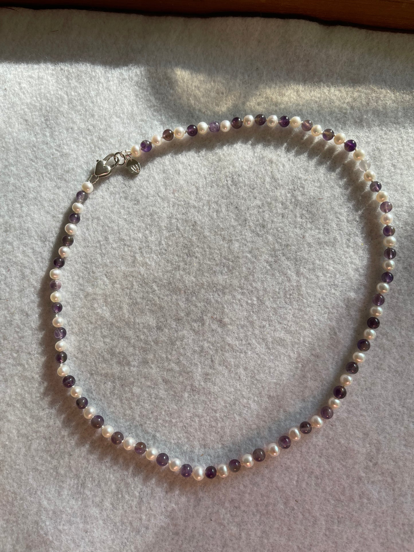Necklace with pearls and purple beads on a light gray surface