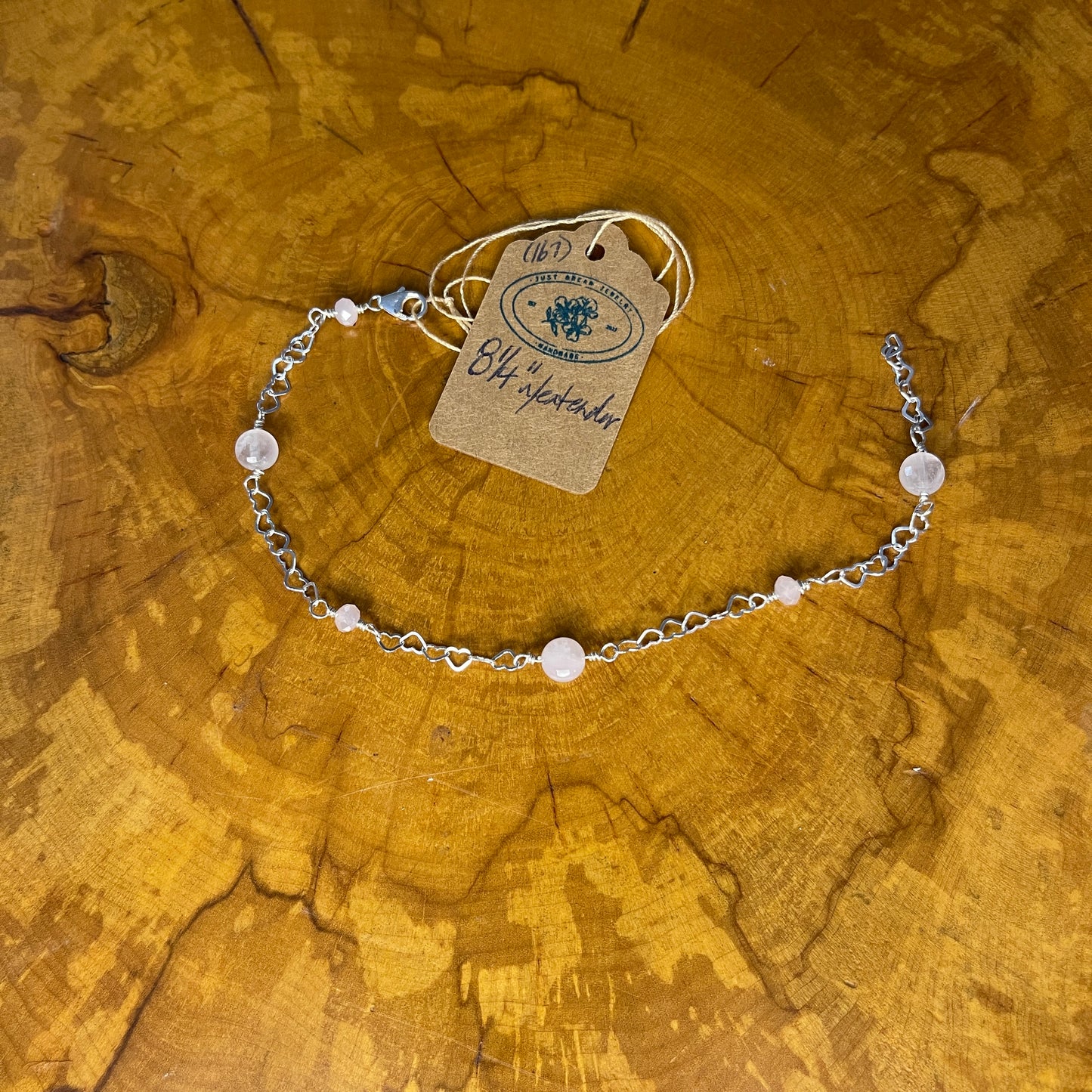 Faceted Rose Quartz on Sterling silver Heart chain and Sterling wire, Sterling Silver Lobster clasp, 8 1/4" on wood