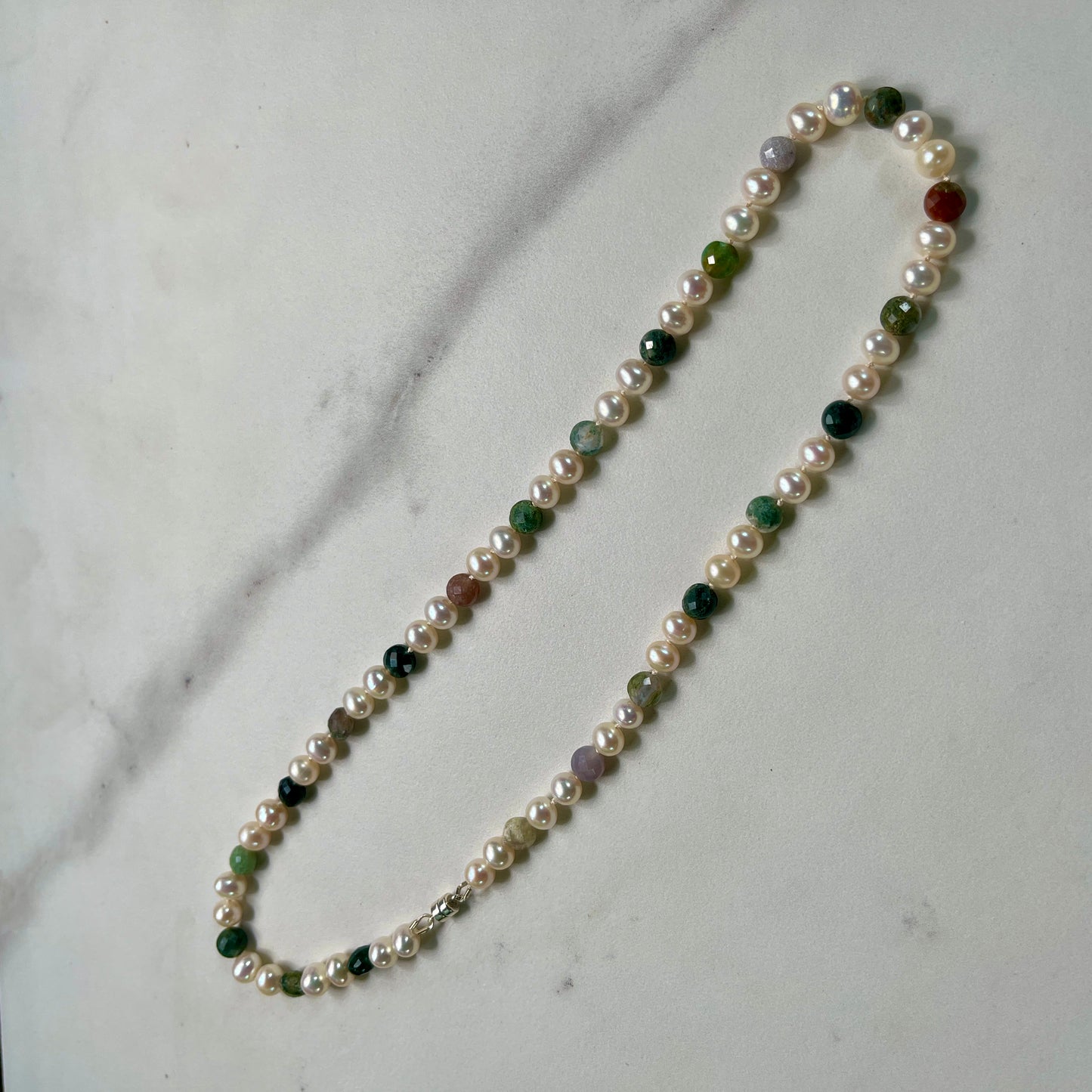Necklace with pearls and multicolored beads on a marble surface