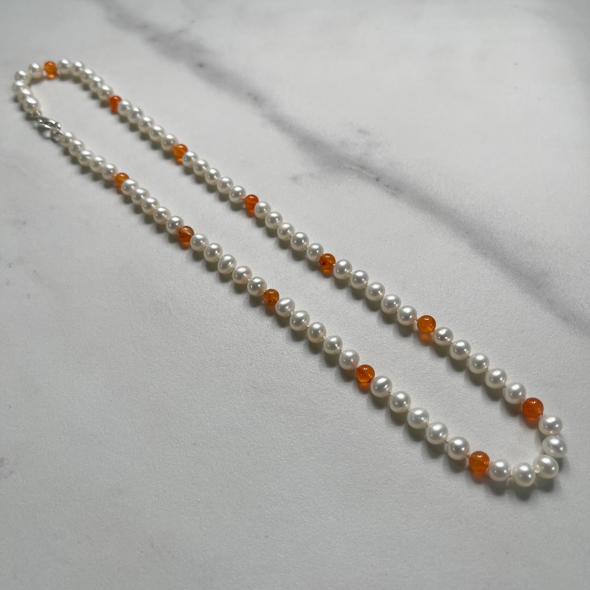 Pearl and Carnelian beaded necklace with on a marble surface