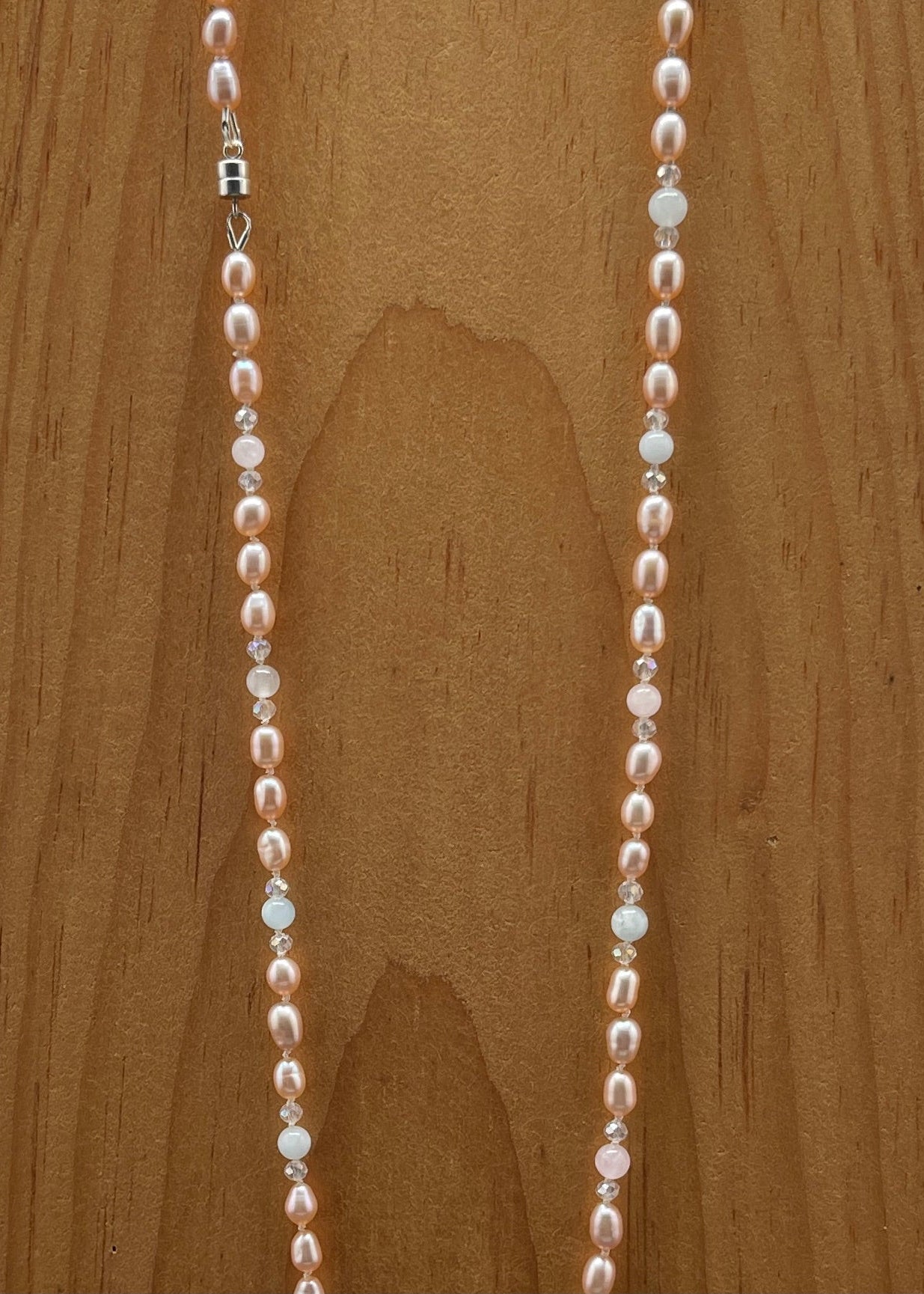 Pearl , Morganite and crystal necklace on a wooden surface