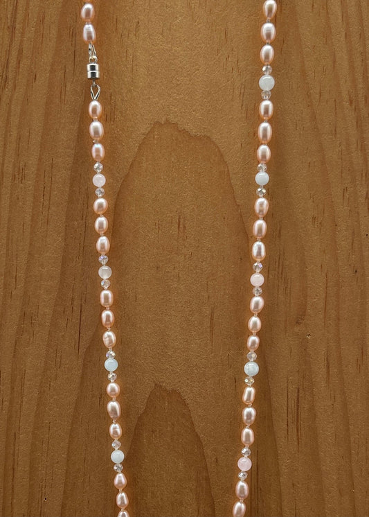 Pearl , Morganite and crystal necklace on a wooden surface