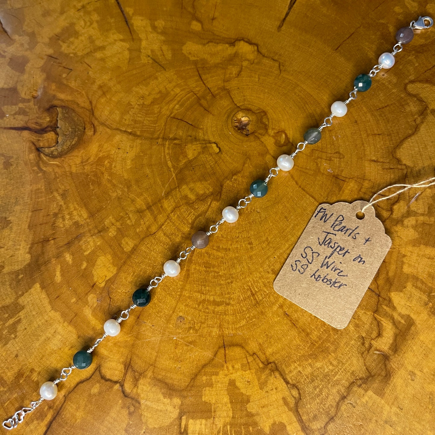 Faceted Multi colored Jasper and White Freshwater Pearls on Sterling Silver wire with Sterling Silver Lobster clasp, 8" with Sterling 1" heart chain extender on wood