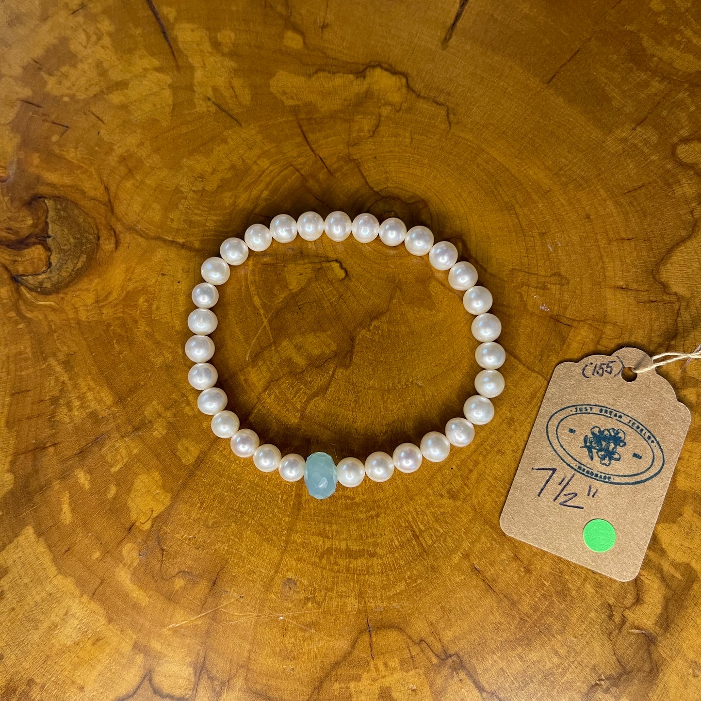 White freshwater Pearls with Aquamarine Rondelle focus bead on elastic, 7 1/2" on wooden surface with tag