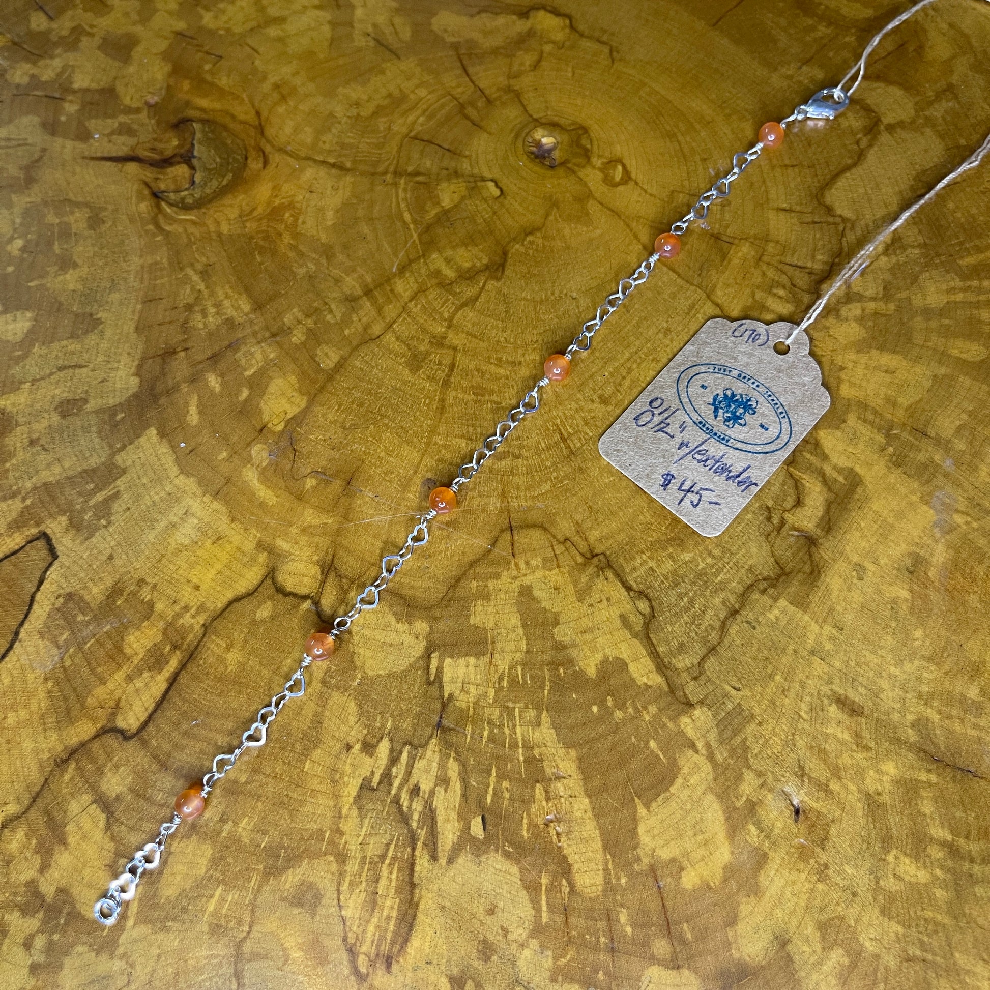 Carnelian rounds on Sterling Silver wire and Sterling Silver Heart Chain 8 1/2", Sterling Silver Lobster clasp on wooden surface with tag