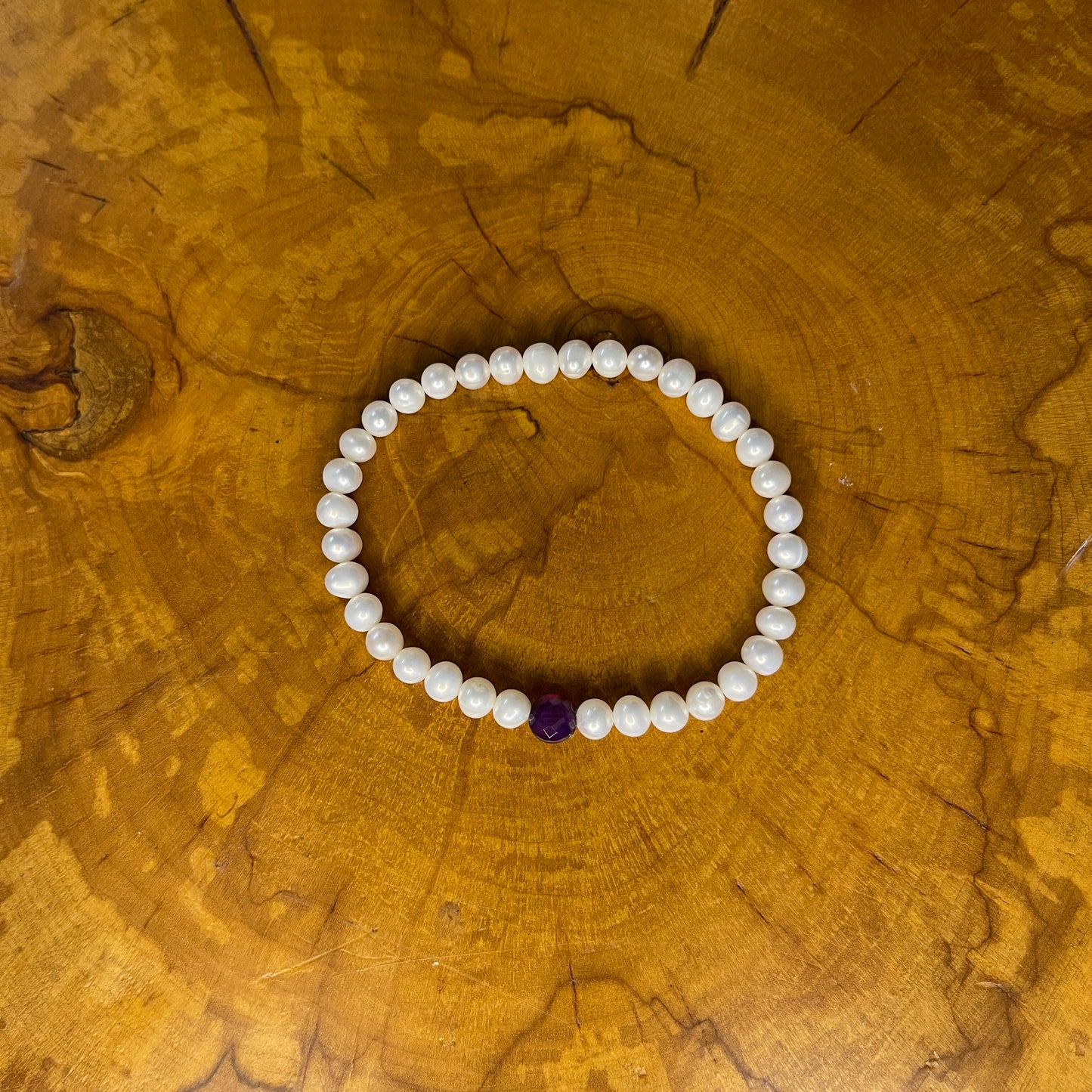 5mm White freshwater pearls with Red Jasper focus bead on elastic, 7 1/4" on wooden surface