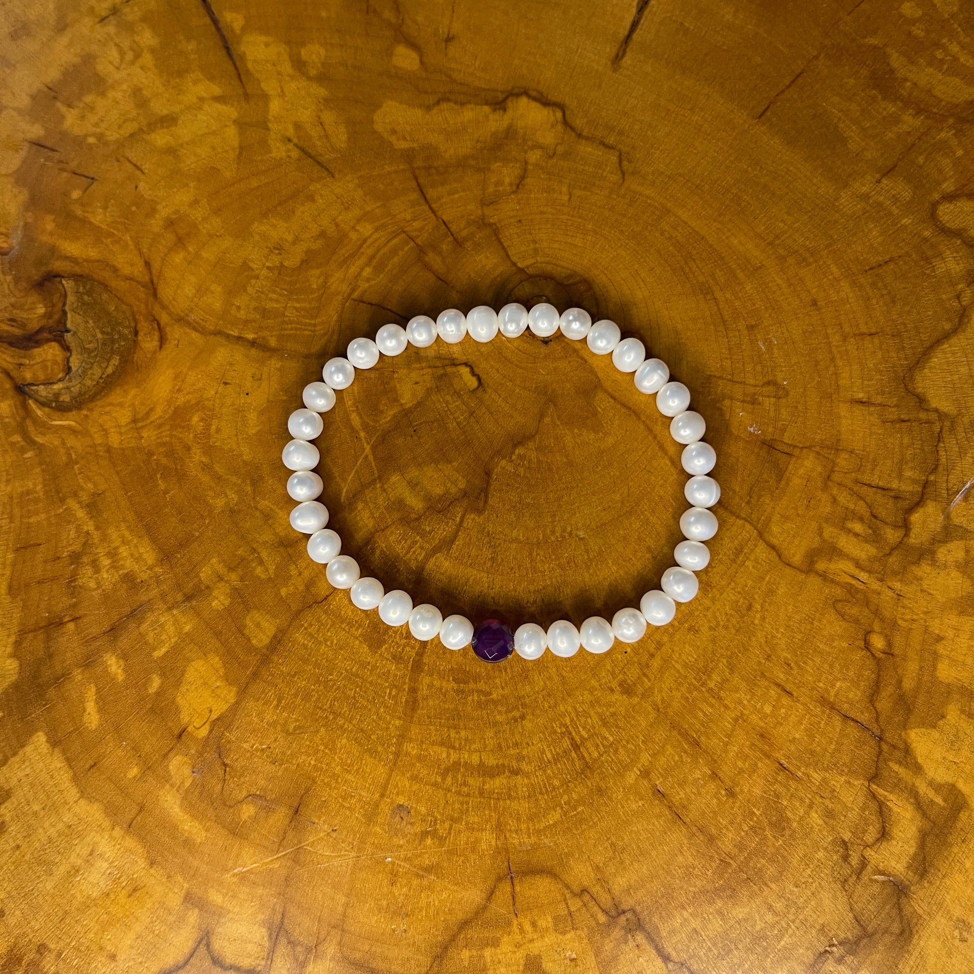 5mm White freshwater pearls with Red Jasper focus bead on elastic, 7 1/4" on wooden surface
