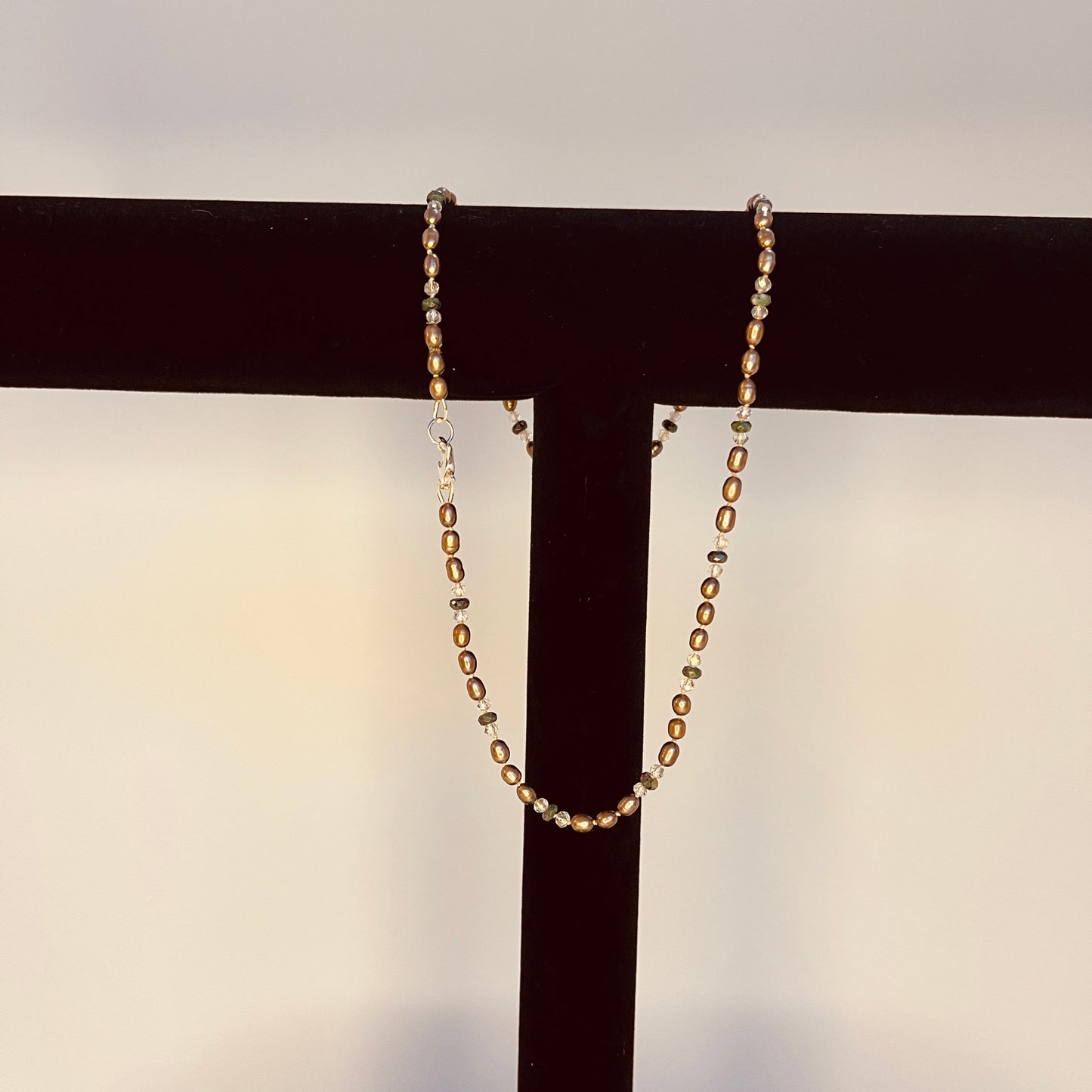 Chocolate Pearls, crystal and green jasper necklace on a black stand with a neutral background