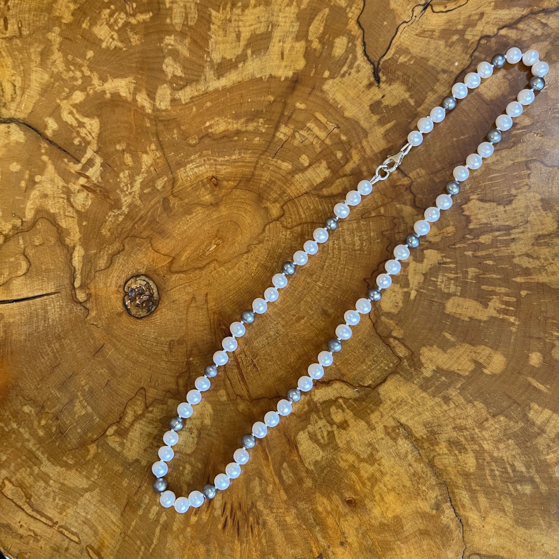 White and Silver Pearl necklace on a wooden slab