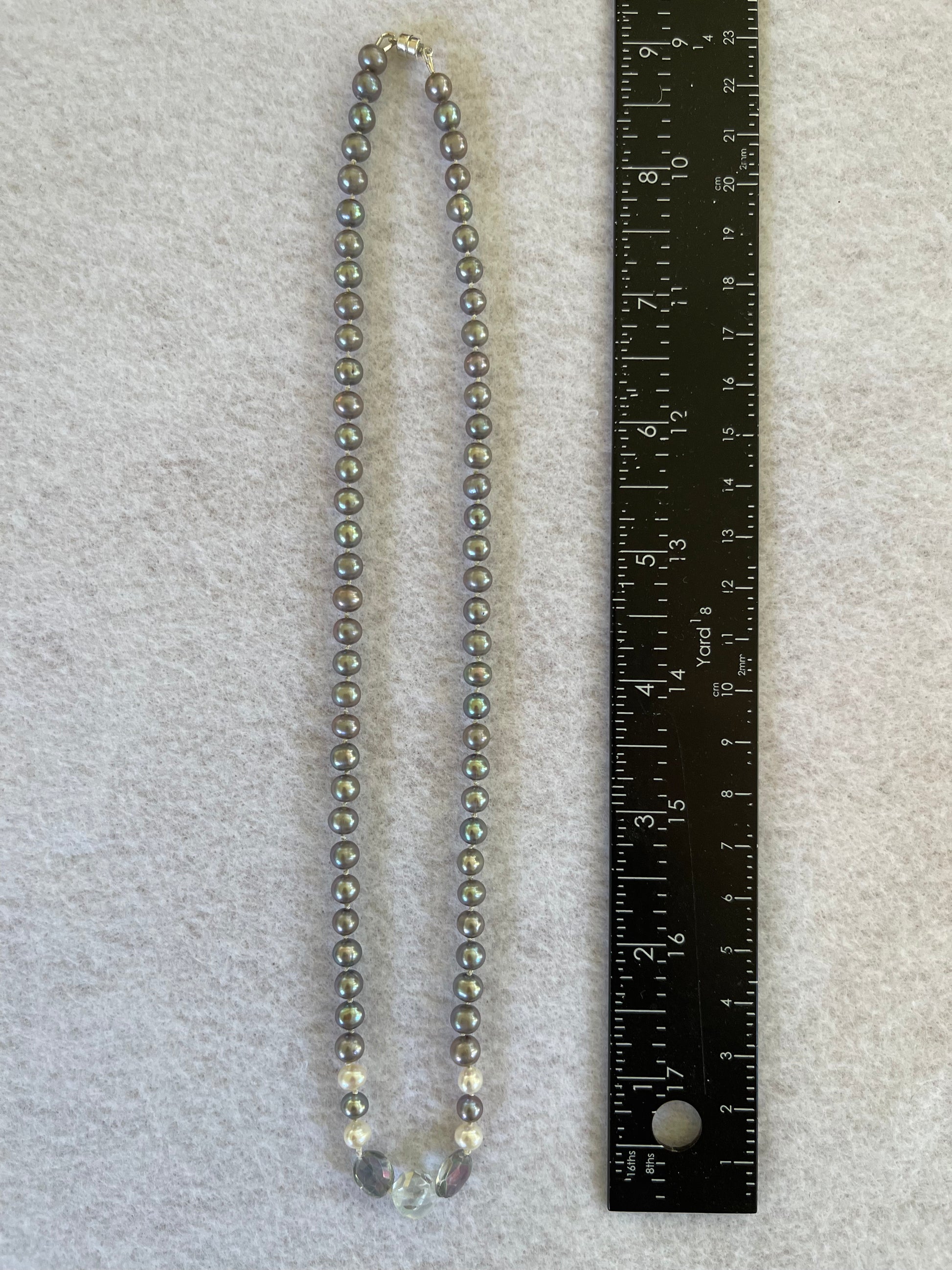Necklace of Silver Peacock pearls with  Aquamarine and Rainbow Tourmaline focus beads on a white surface with ruler