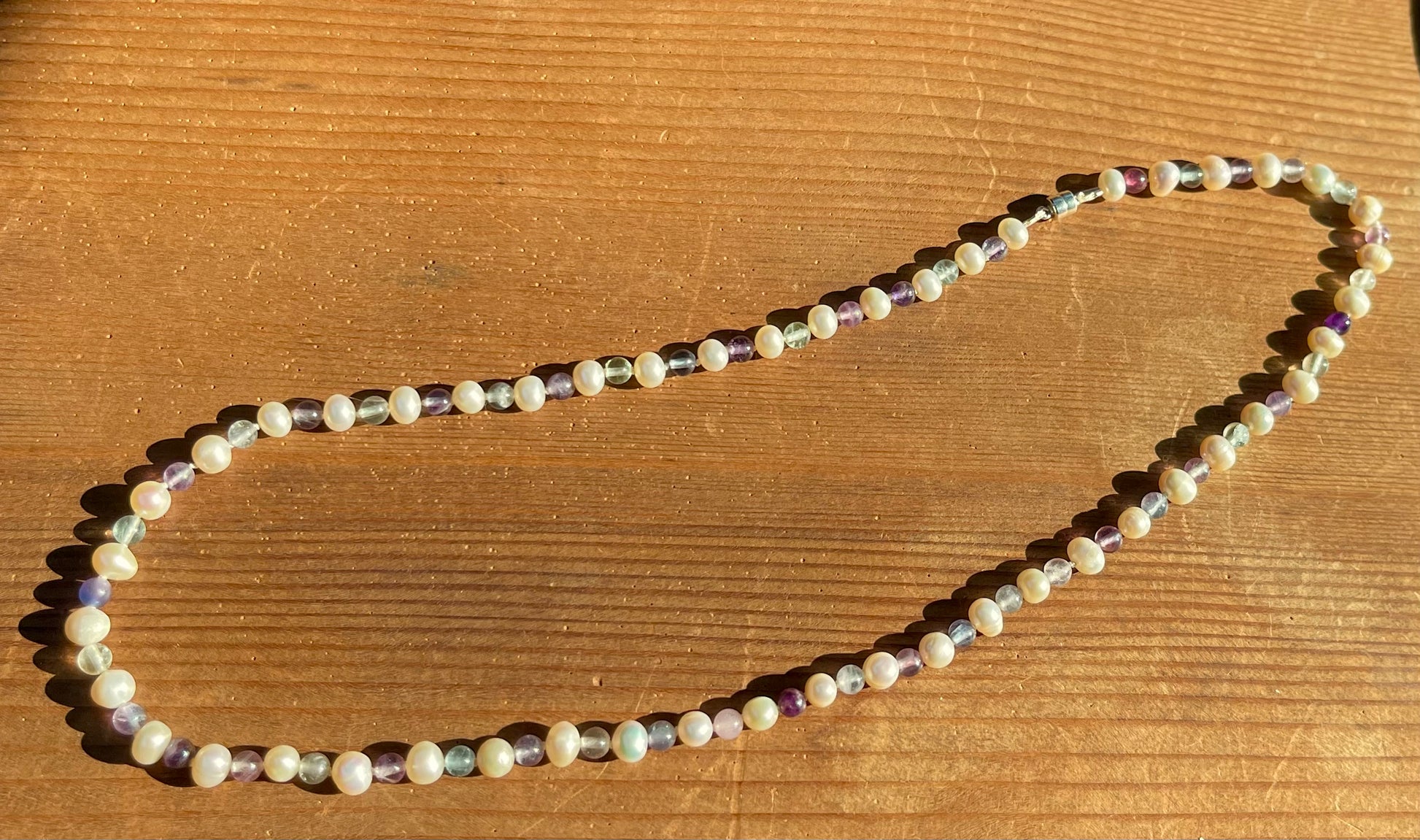 White Pearl and Fluorite Beaded necklace on a wooden surface