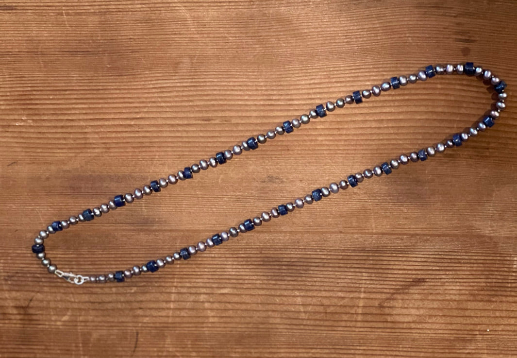 Necklace with blue lapis and silver Pearl beads on wood