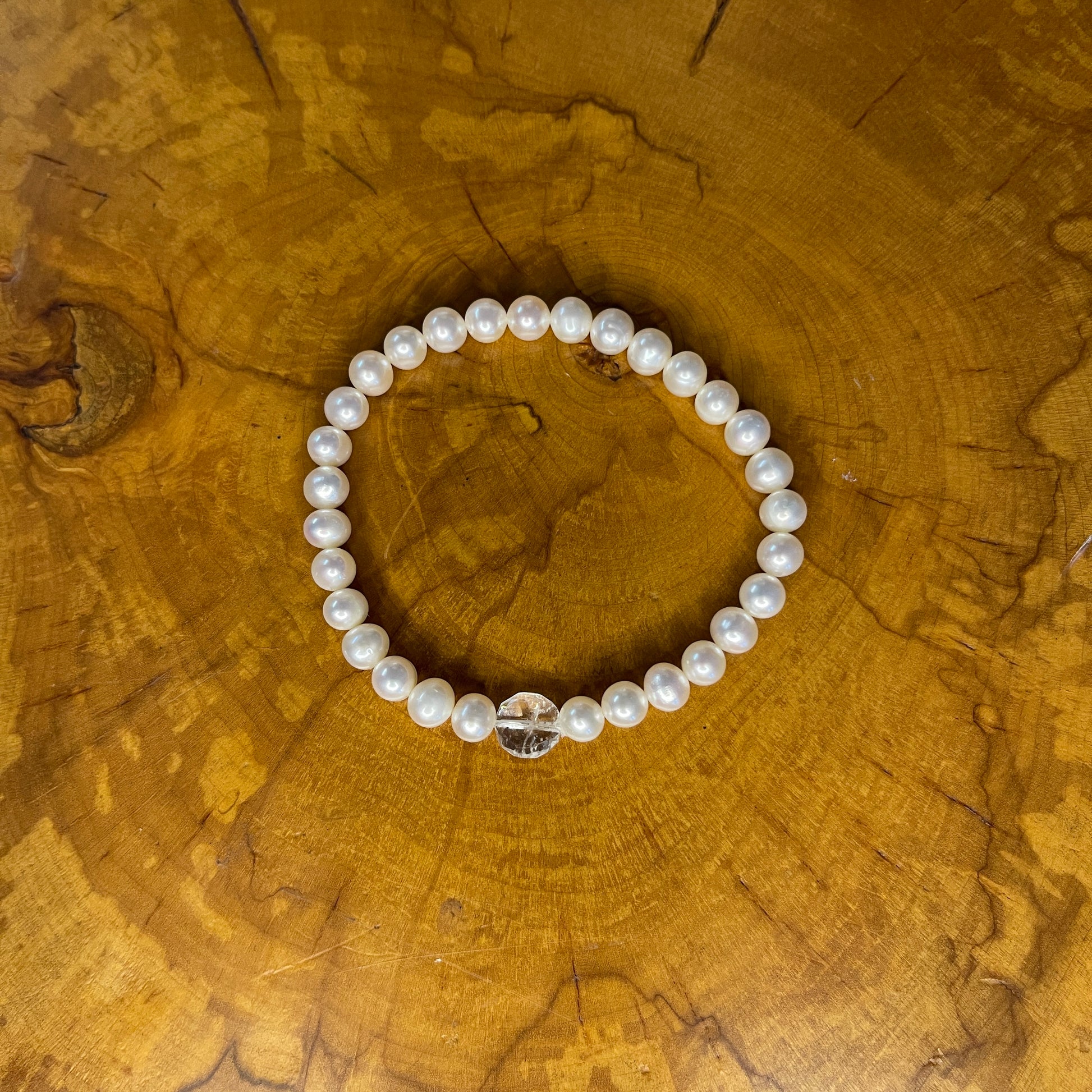 White freshwater Pearls with Quartz focus bead on elastic, 7 1/4" on wooden surface