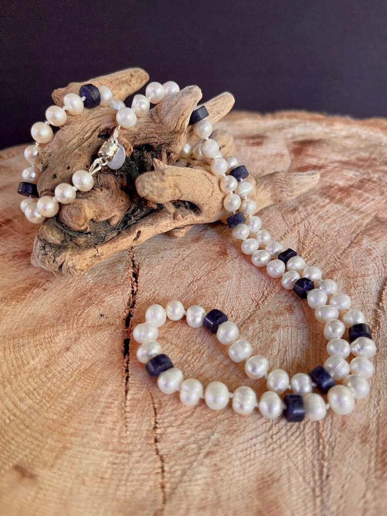 White Pearl and Lapis Lazuli heishi beaded  necklace (without the matching stretchy bracelet )on a wooden surface with a crystal background