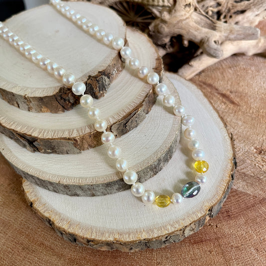 Pearl necklace with citrine and rainbow tourmaline accents on a wooden surface
