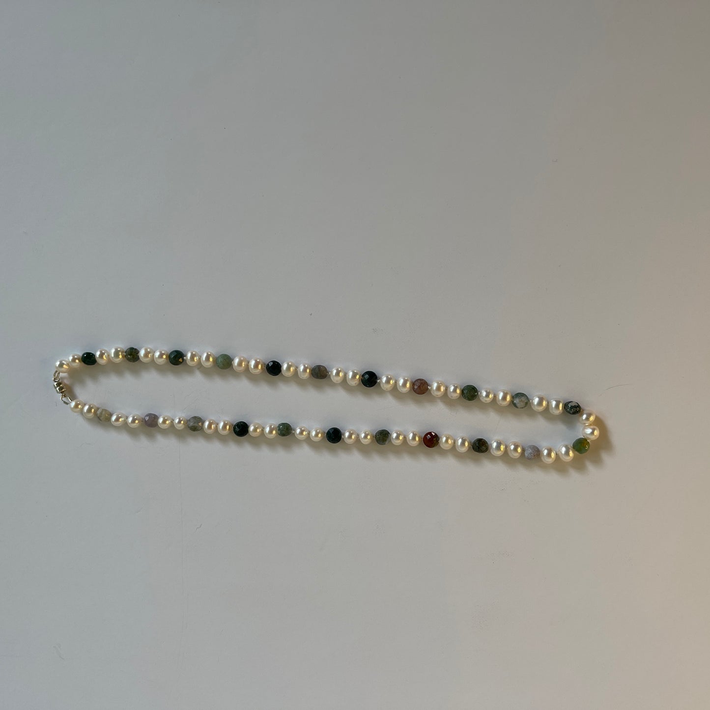 Pearl Beaded necklace with multicolored Jasper beads on a plain background