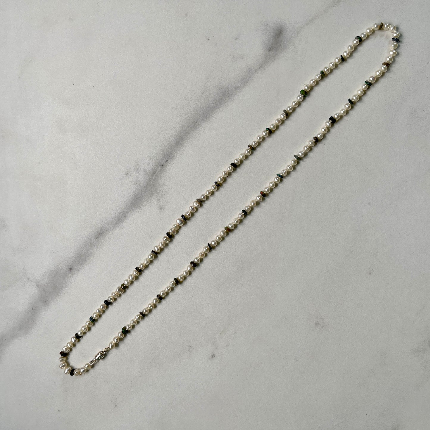 Necklace with small Pearl and Black Opal beads on a marble surface