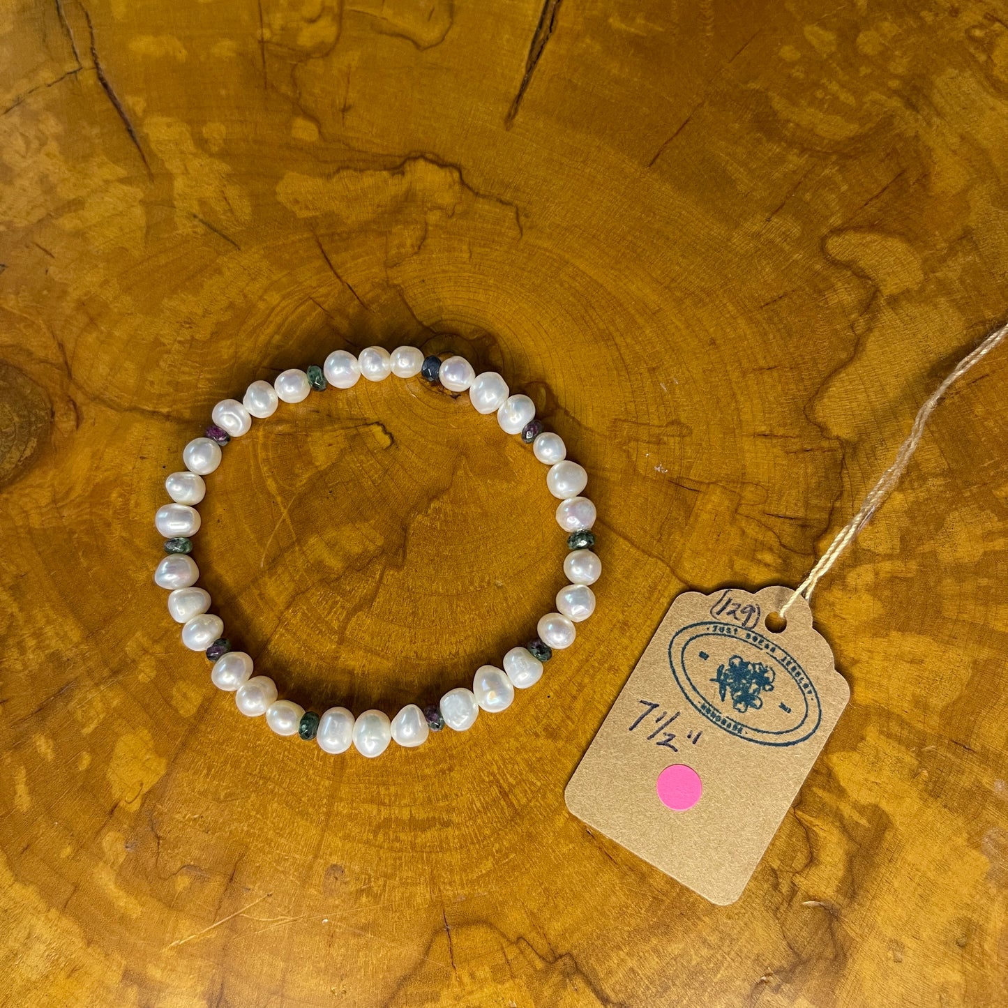 White freshwater Pearls with tiny faceted Jasper on elastic, 7 1/2" on a wooden surface