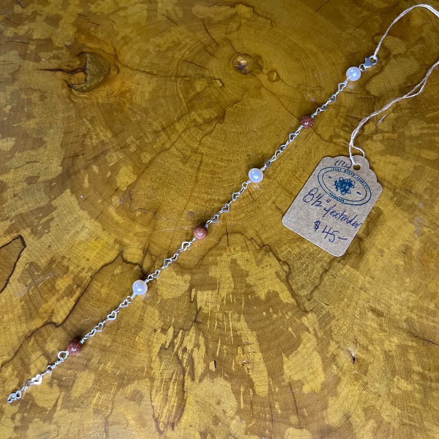 Goldstone and Freshwater Pearl on Sterling Silver Heart chain , Sterling Silver lobster clasp,8 1/2" on wooden surface with tag