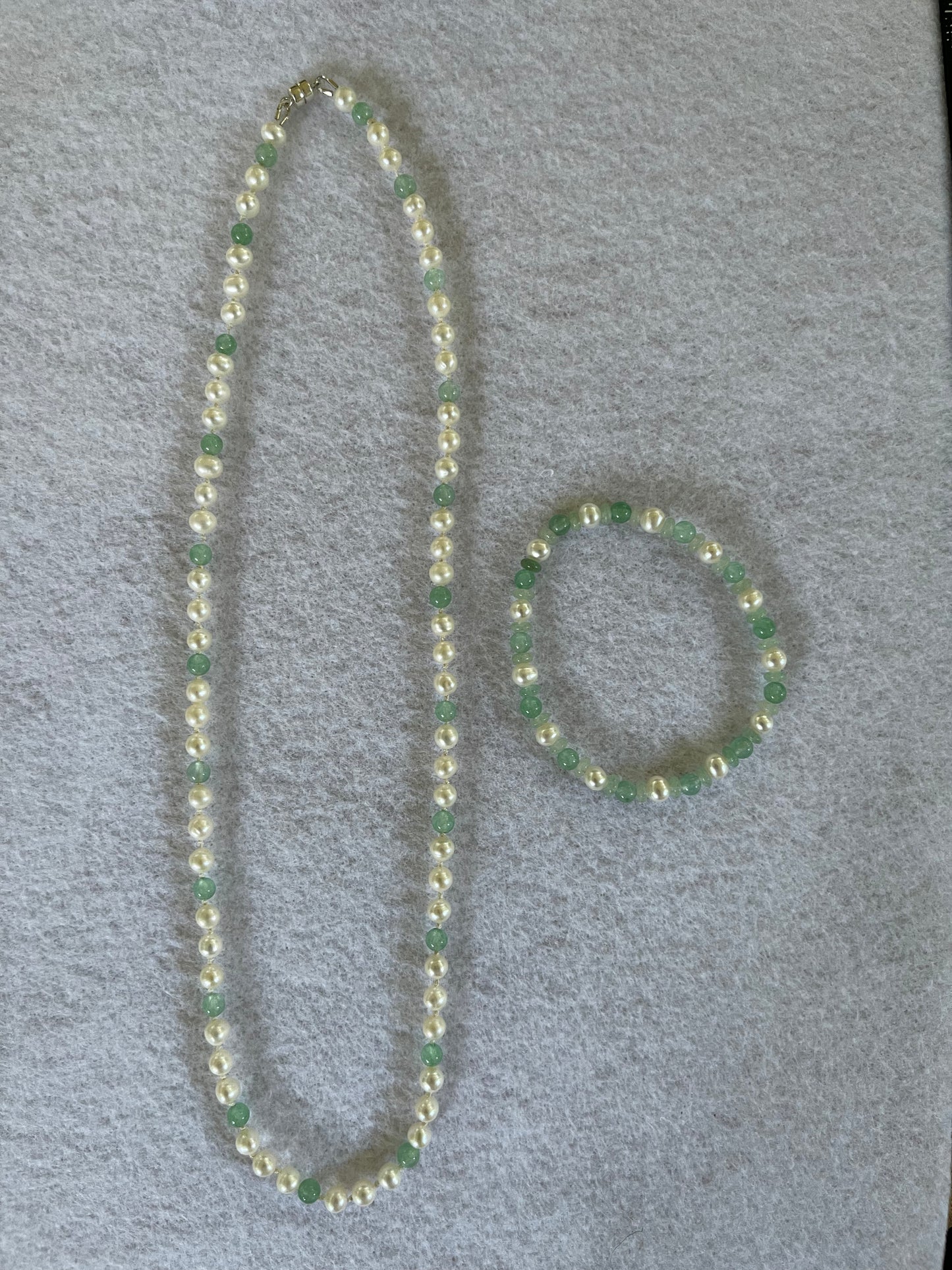 White Pearl and green aventurine beaded necklace and bracelet set on white background
