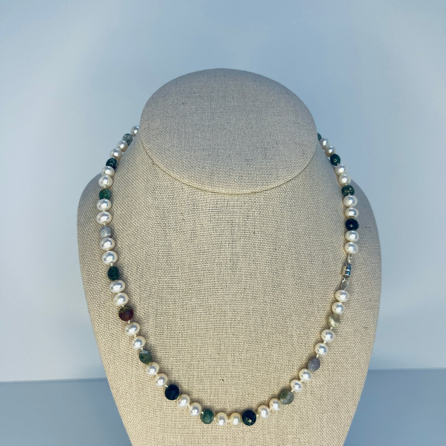 Pearl and multi colored faceted Jasper necklace on a mannequin bust against a plain background
