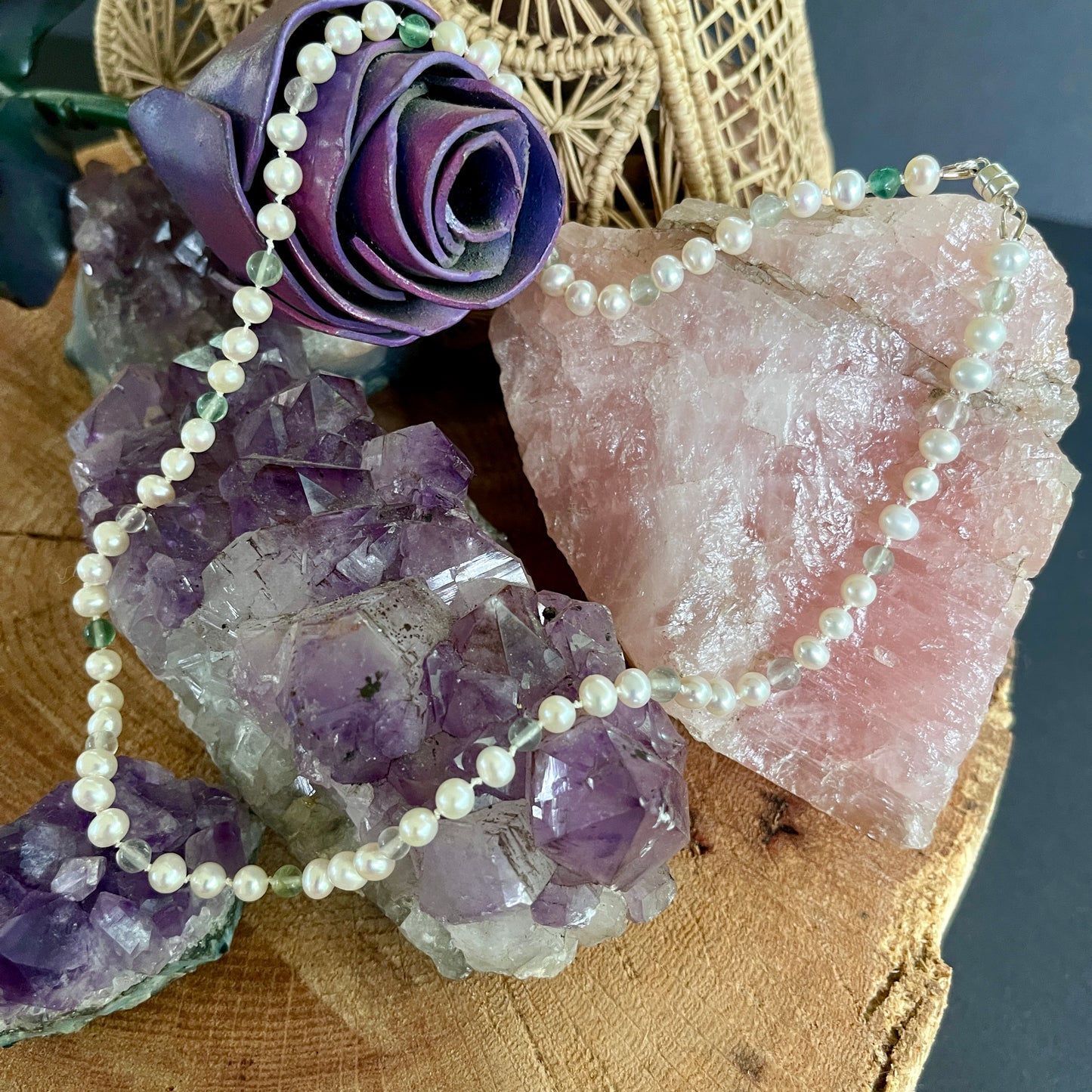 Pearl  and fluorite necklace on a display with purple flowers and crystals