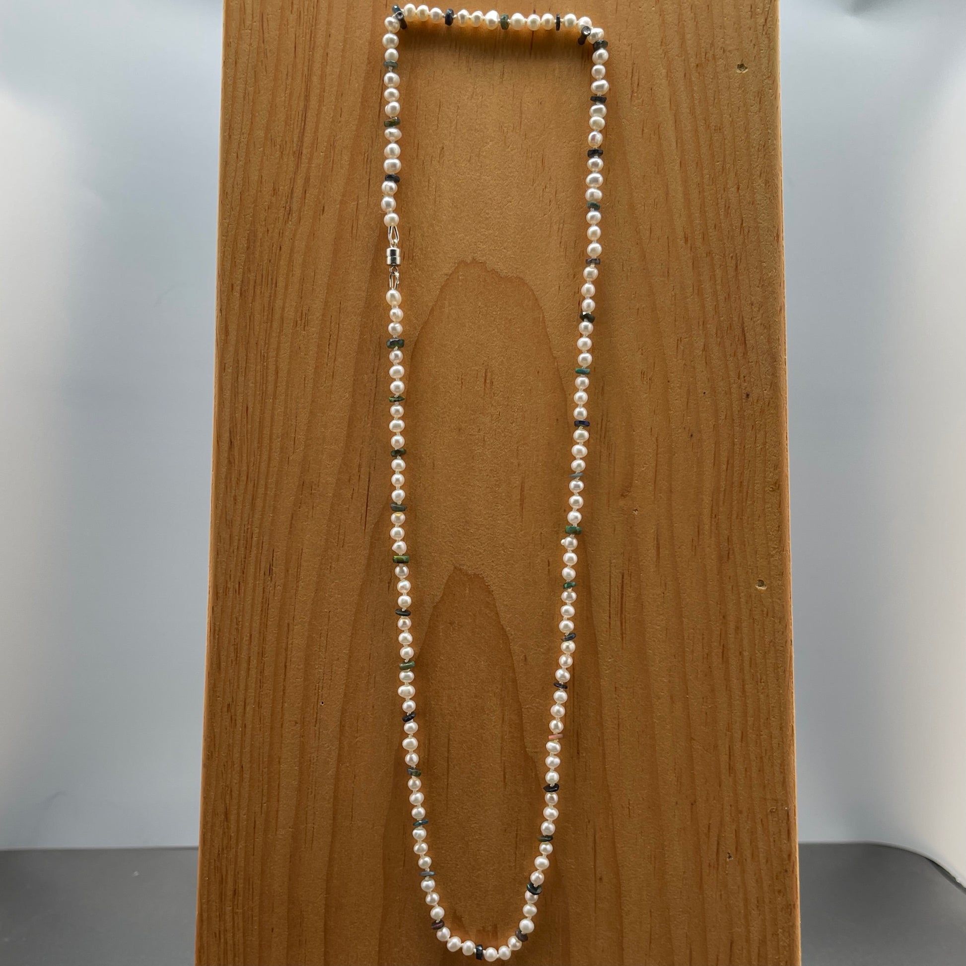 Pearl necklace on a wooden block with a neutral background