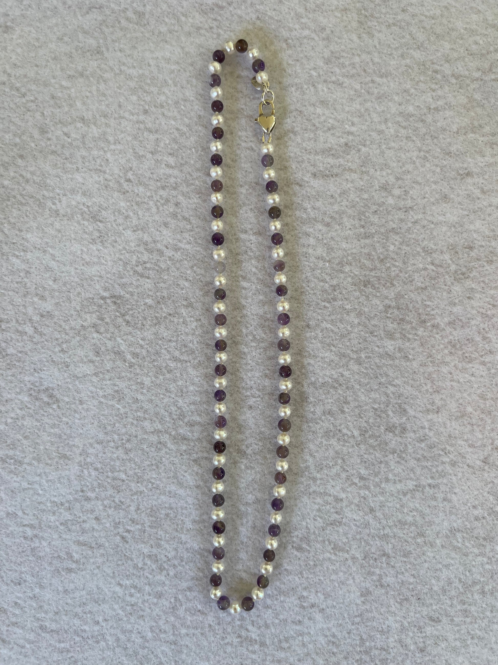 Necklace with alternating White Pearl and Amethyst beads on a gray background