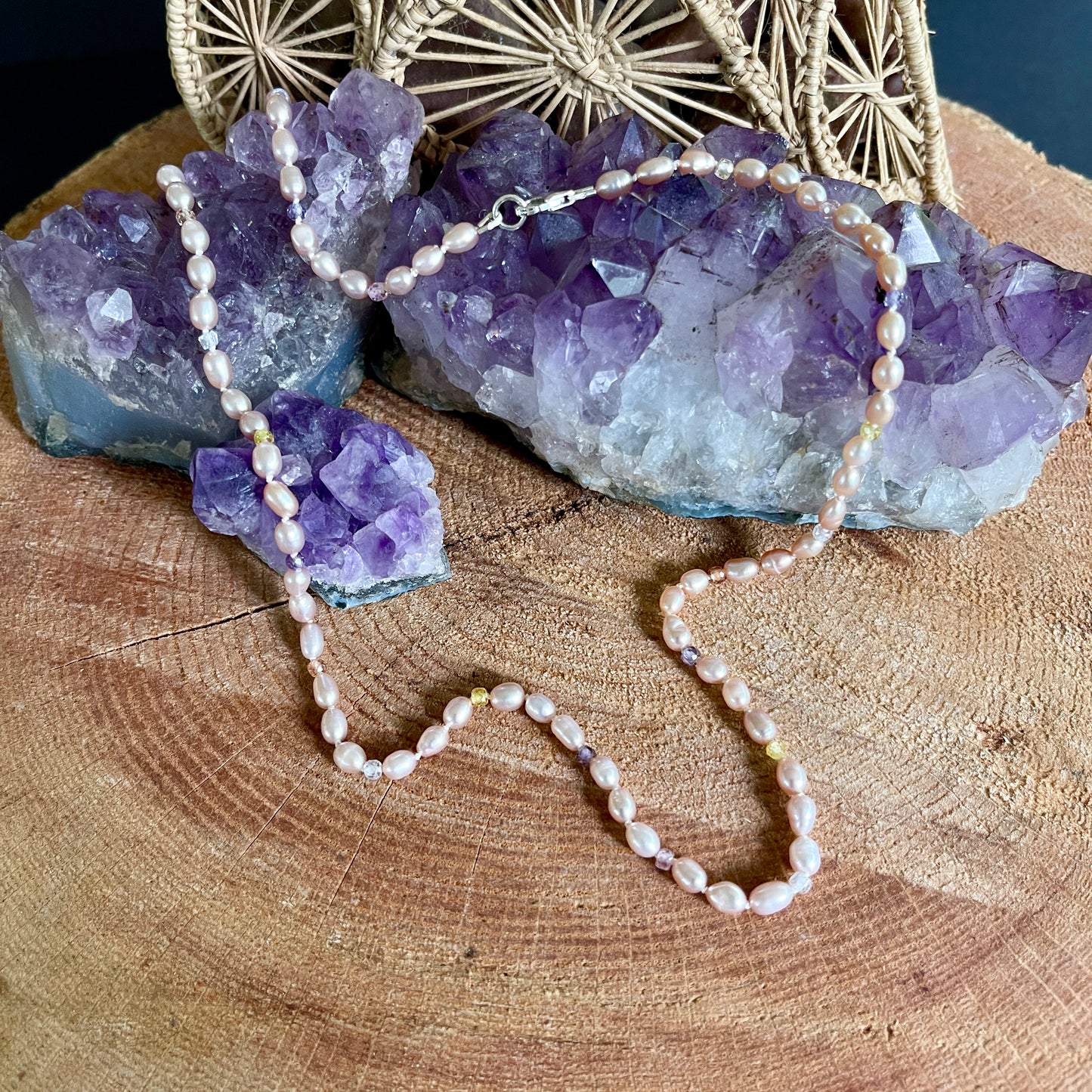 Necklace with pink  Pearl and CZ beads on a wooden surface with purple crystal rock and gold decorative item.