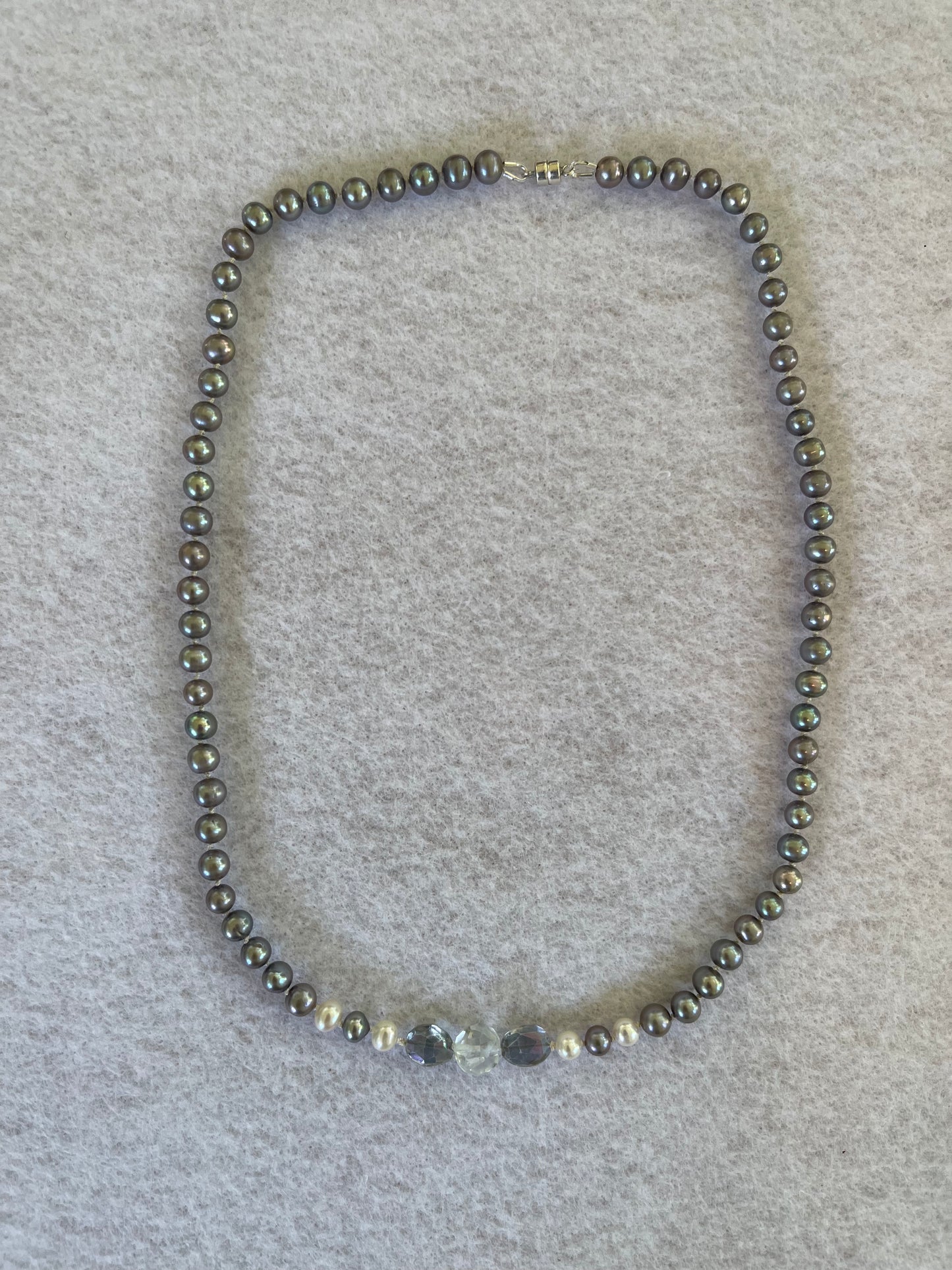 Necklace of Silver Peacock pearls with  Aquamarine and Rainbow Tourmaline focus beads on a white surface