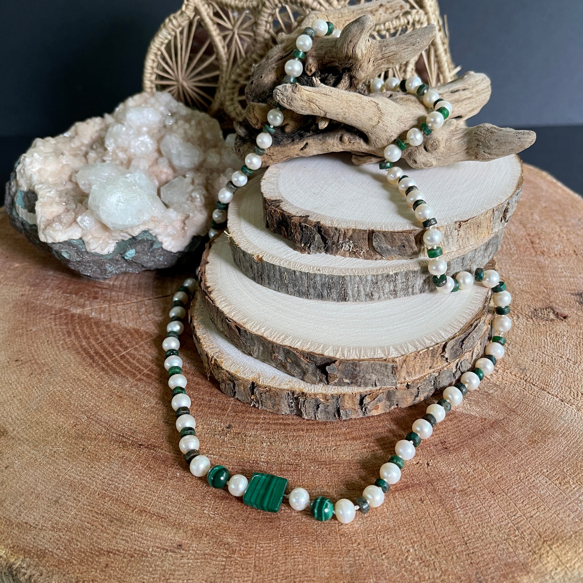Necklace  of Malachite  and White Pearls beads on a wooden surface with natural elements