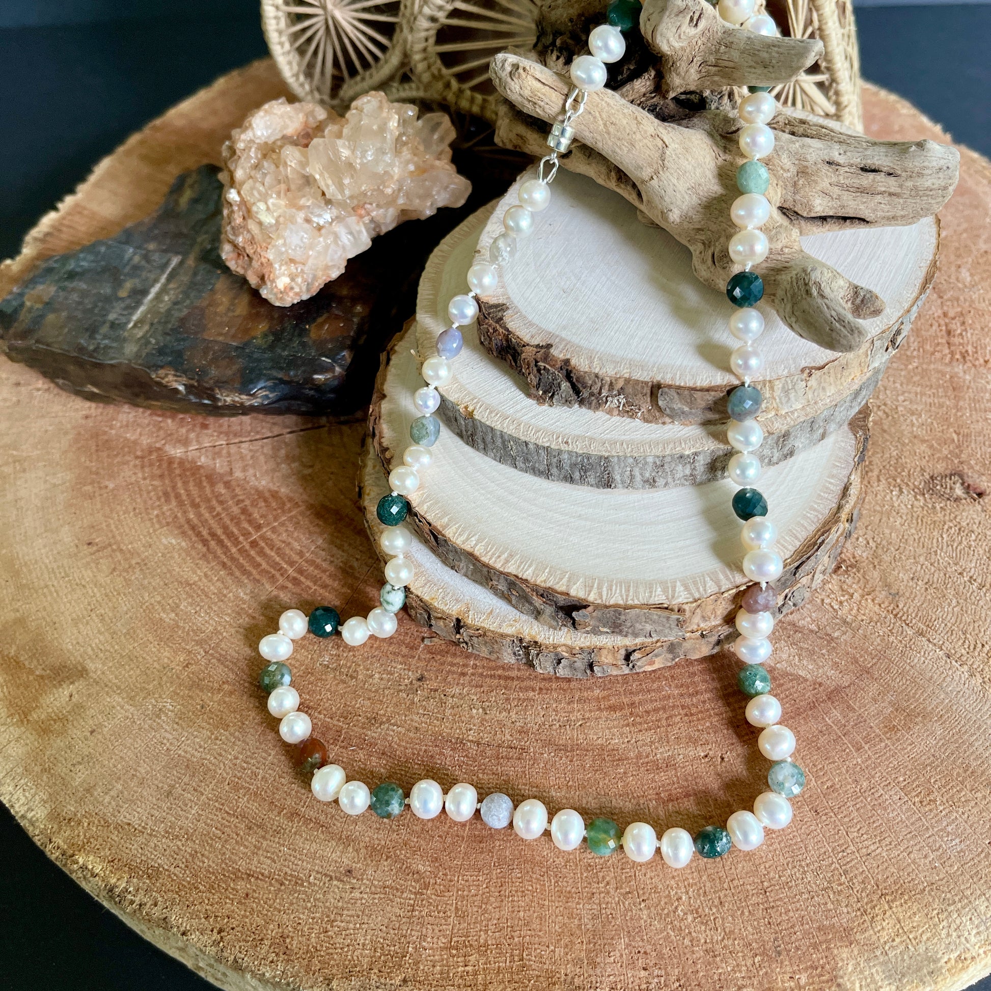 Necklace with Pearls and multicolored Jasper beads on a wooden surface with natural elements