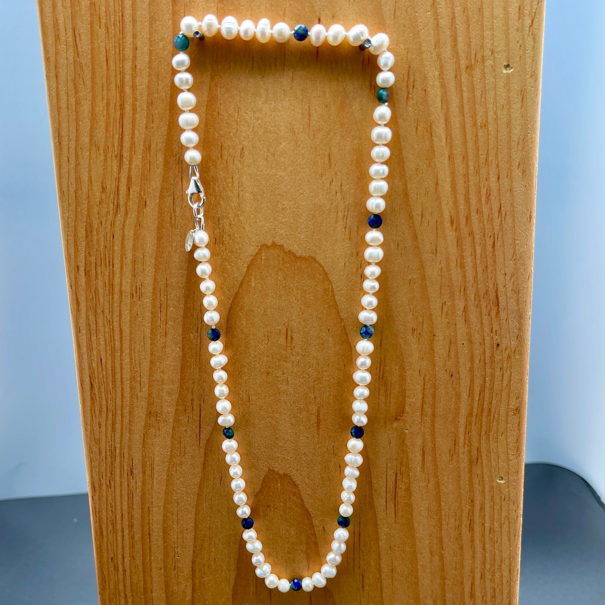 Pearl necklace with blue  Jasper accents on a wooden block