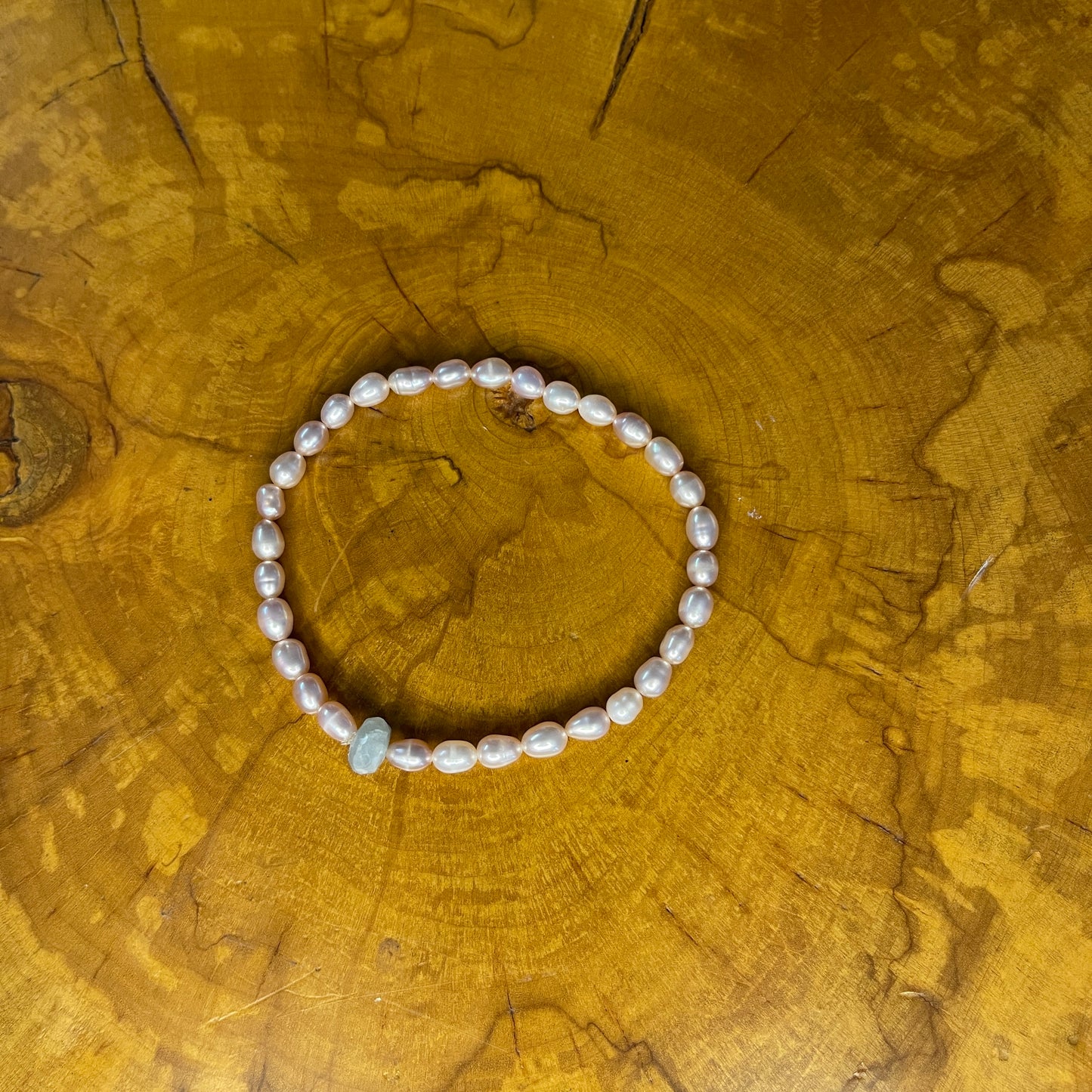 Mauve freshwater Pearls with Blue Chalcedony focus bead on elastic, 7 1/2" on elastic, 7 1/2" on a wooden surface