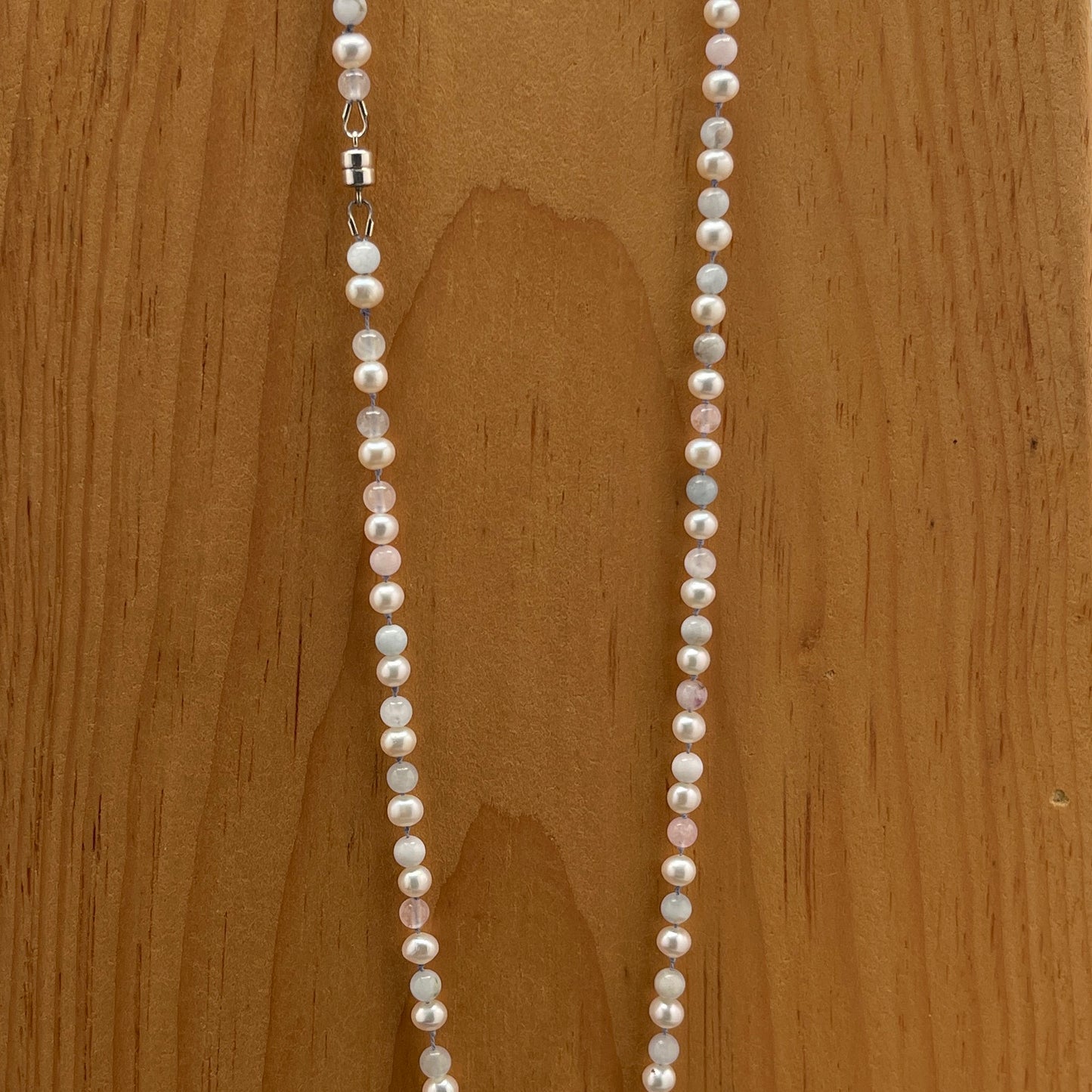 Pearl and Morganite necklace on a wooden surface